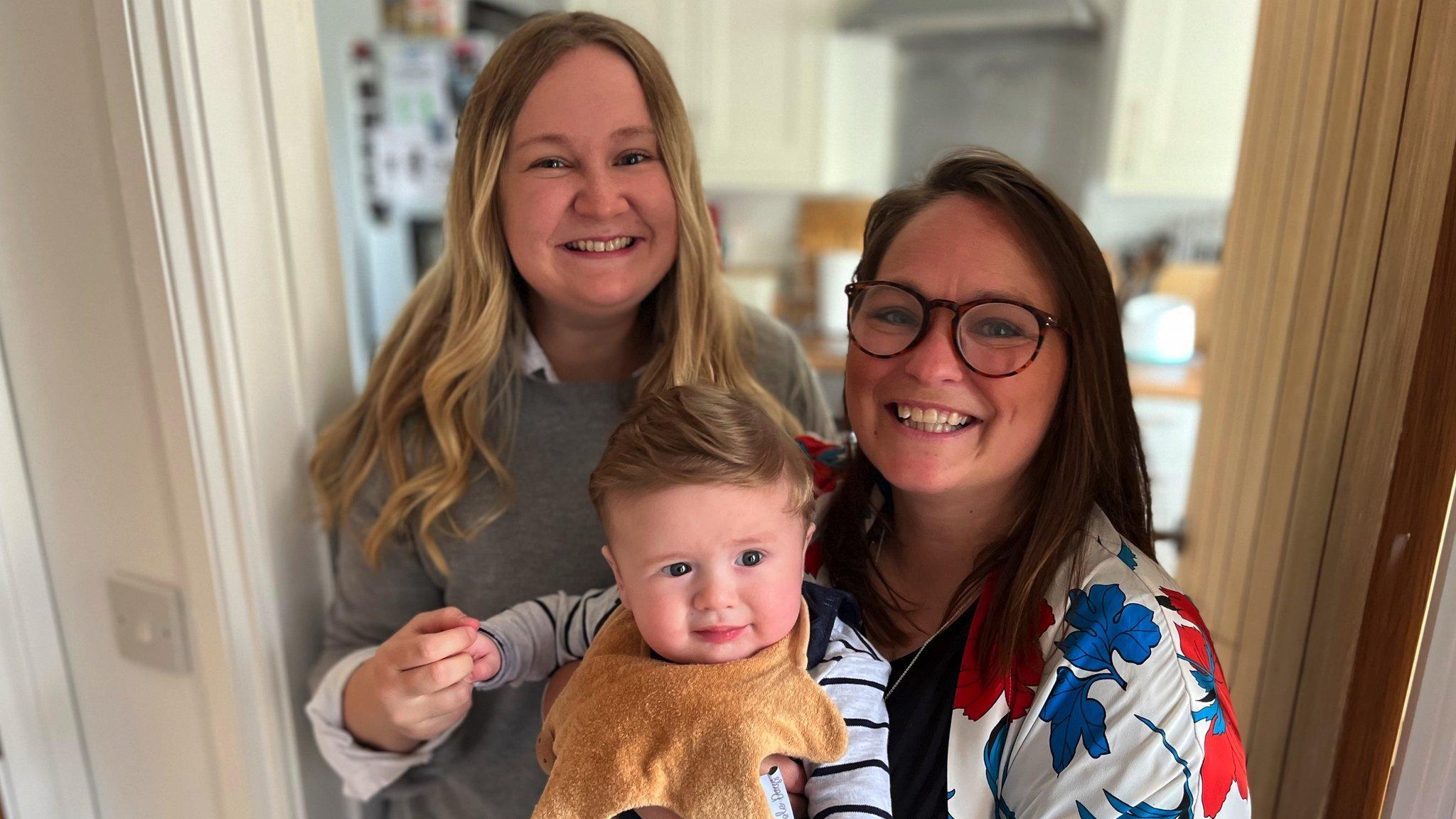 A baby is held by his two mums