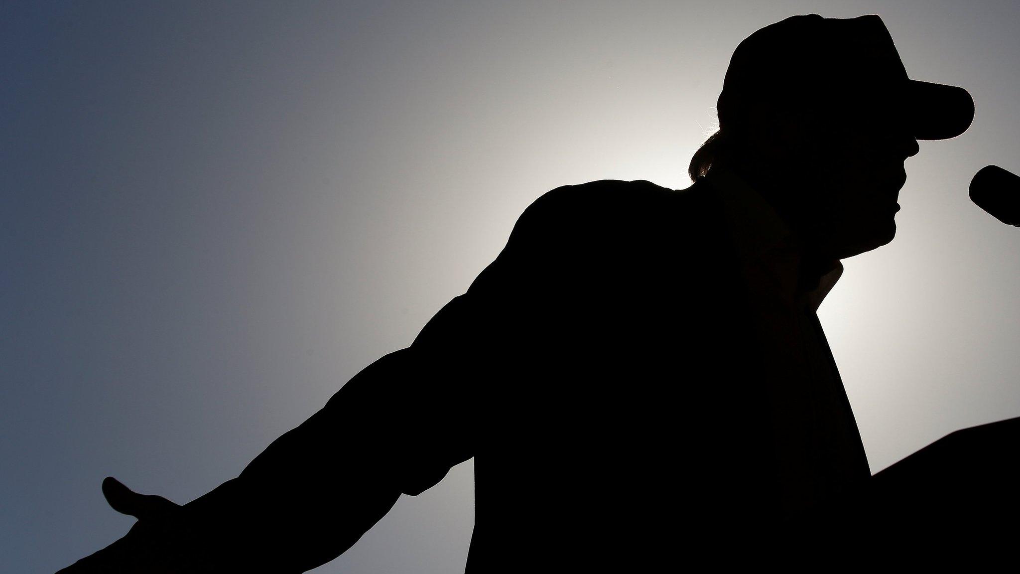 Donald Trump - in silhouette - speaks at a rally