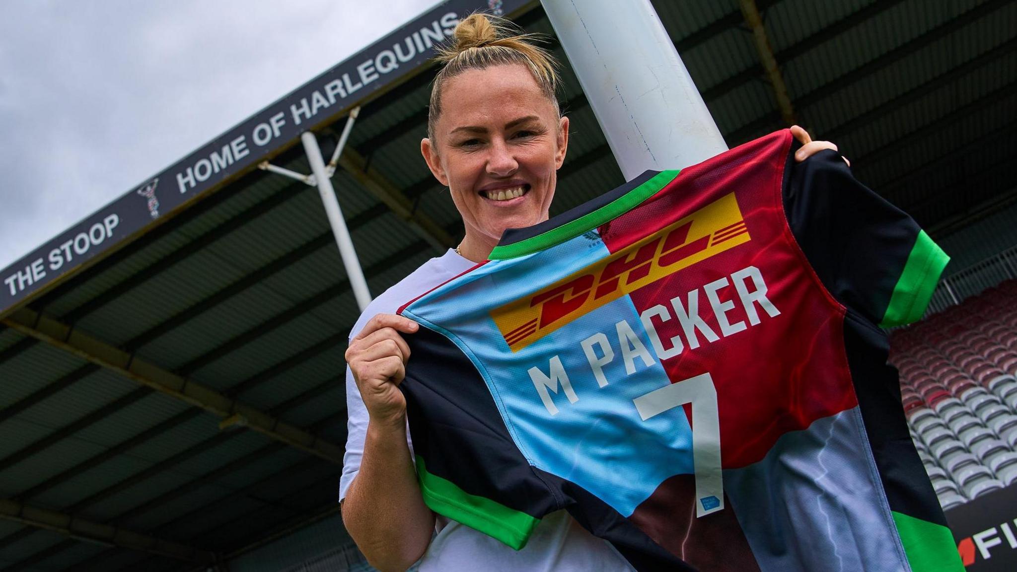 Marlie Packer holds up a Harlequins shirt with her name on it