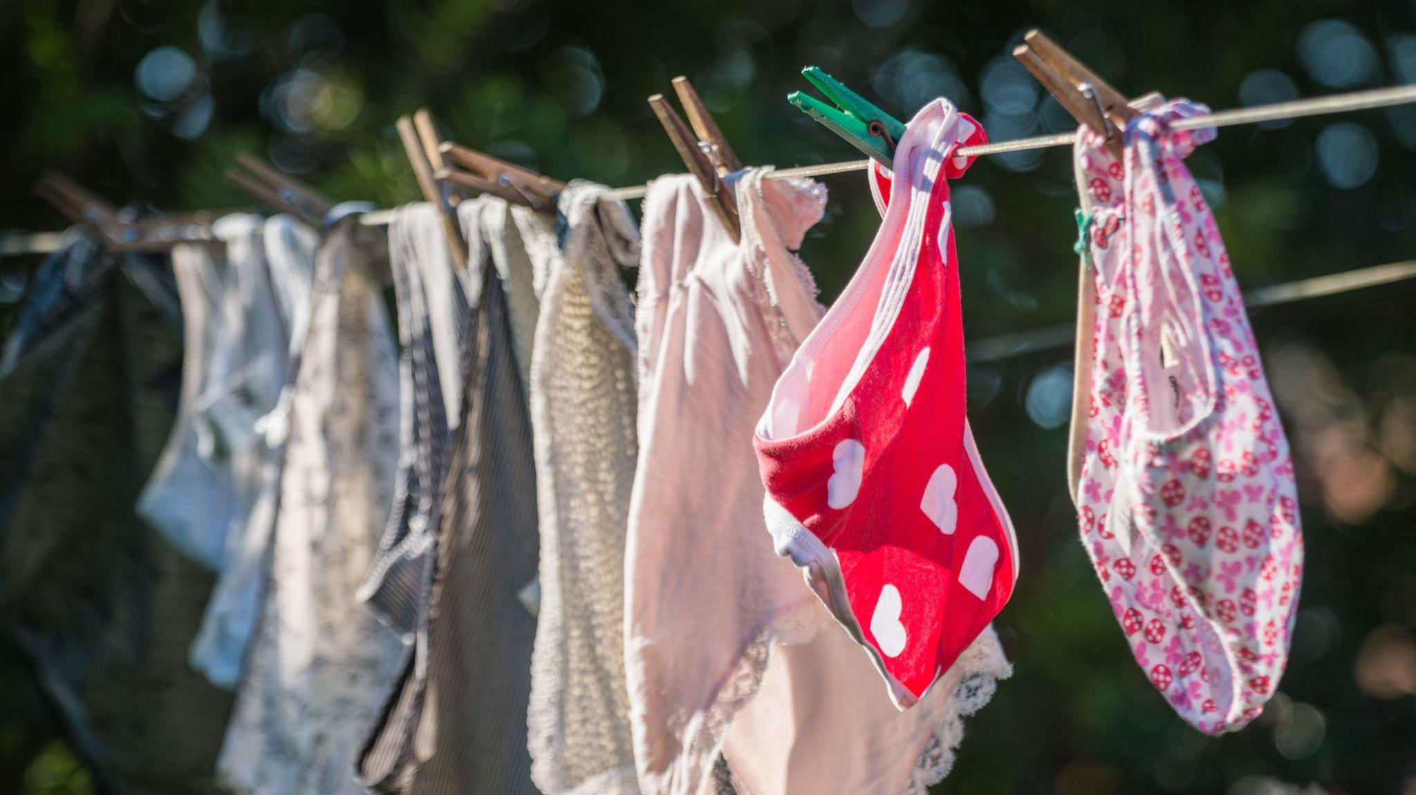 Colourful underwear hanging on a washing line, clipped with wooden pegs. 