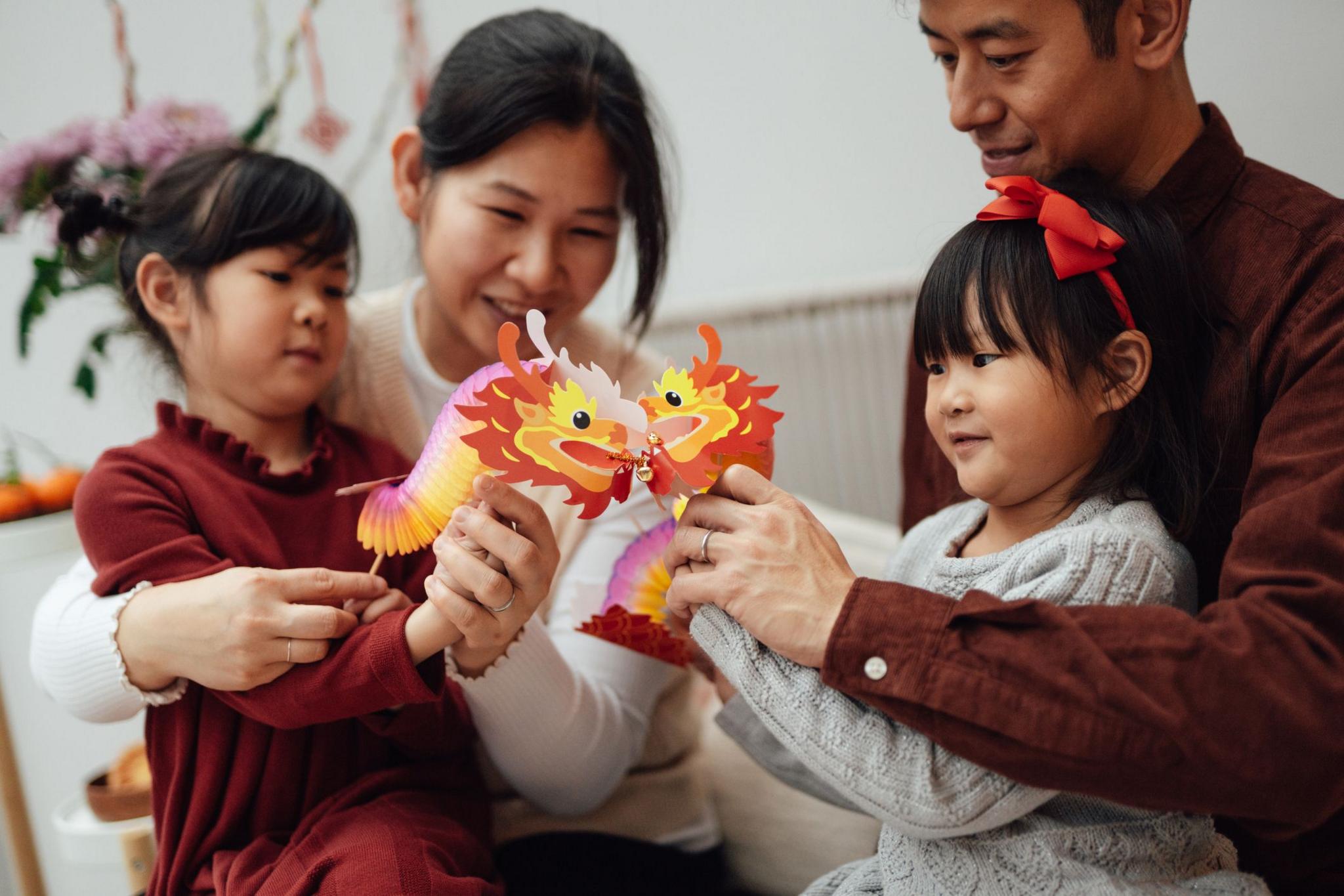 Children with their parents playing with paper dragons.