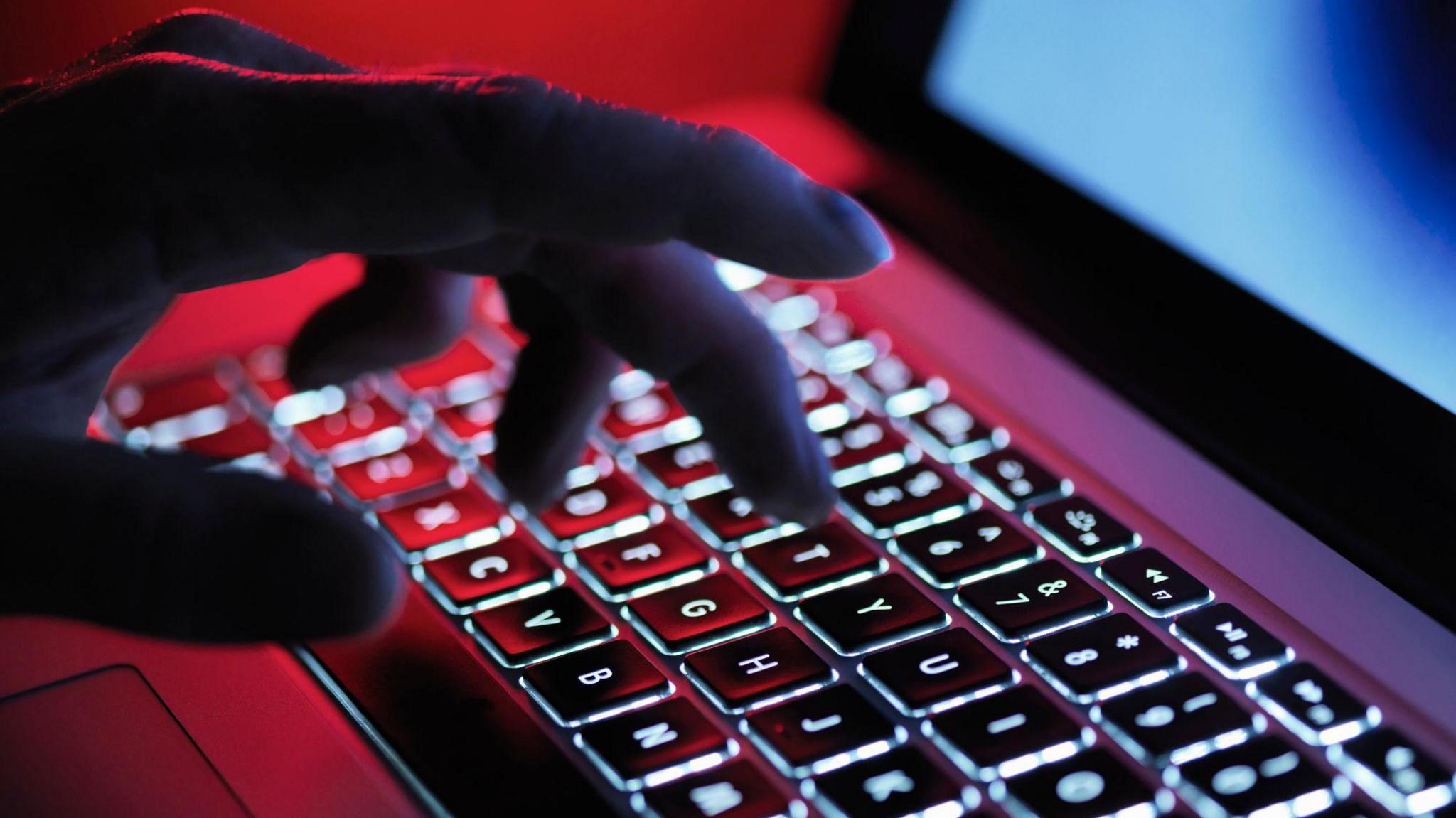 Stock image of and typing on a laptop computer at night.