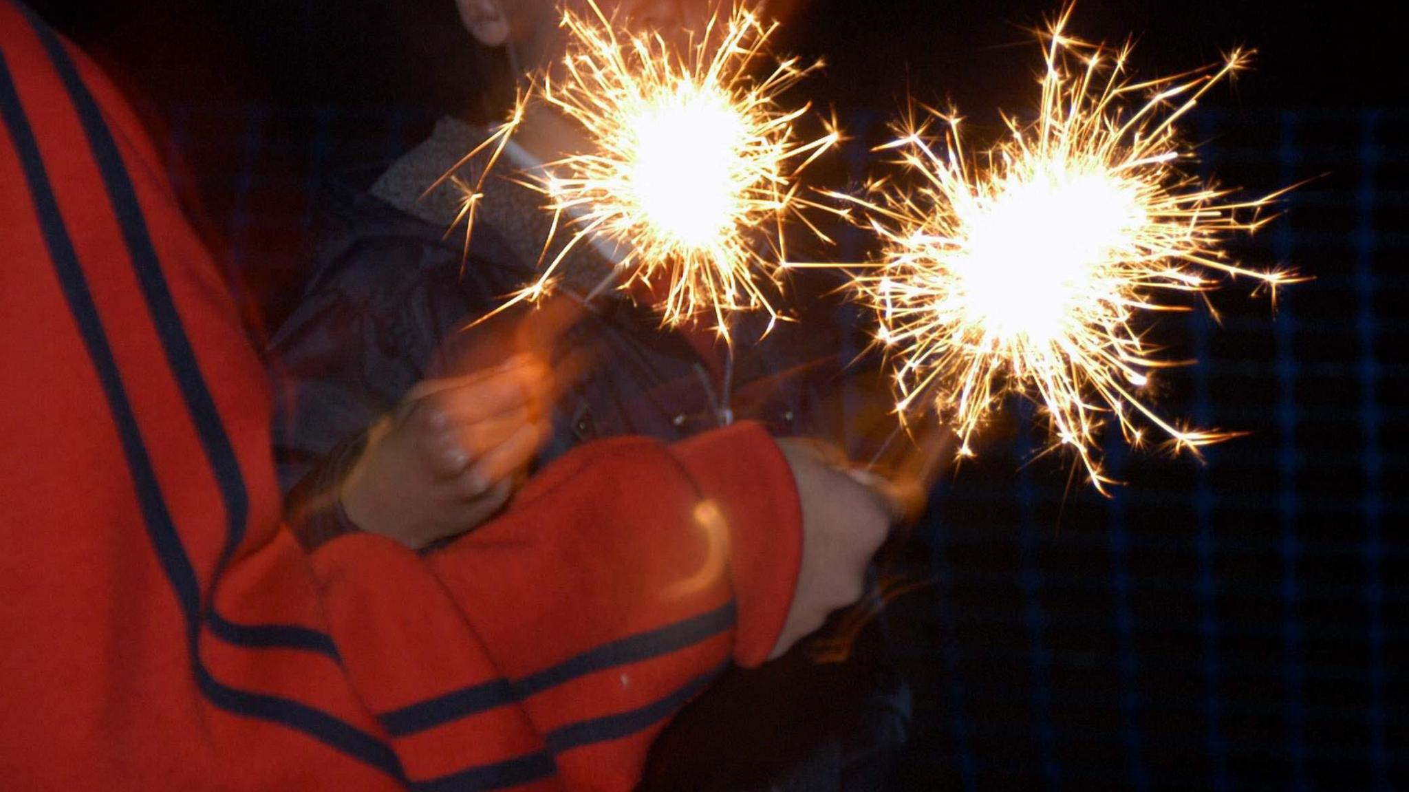 A close up photo of two lit sparklers