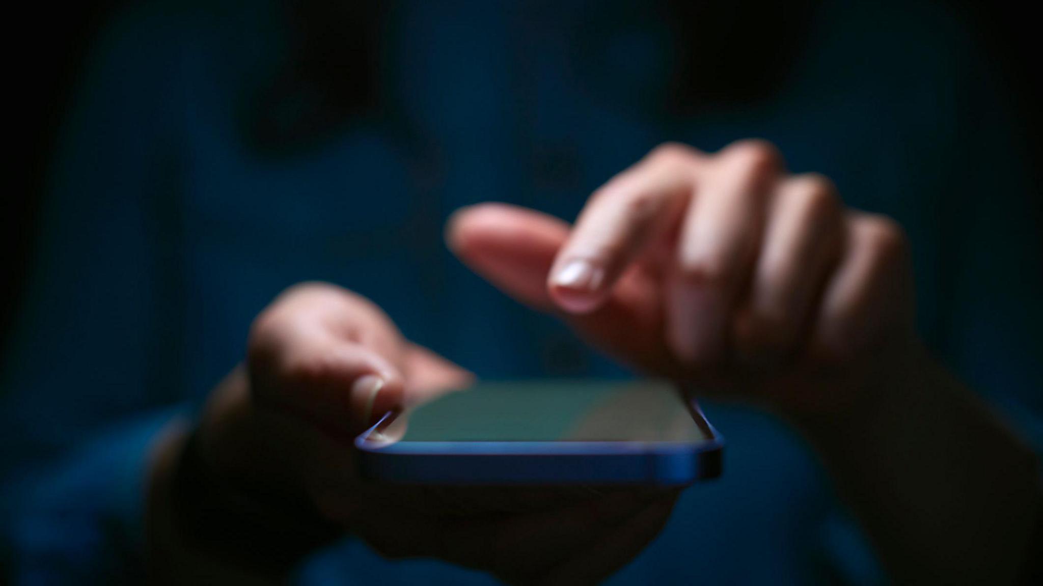 A file photo showing blurred female hands holding a mobile phone.