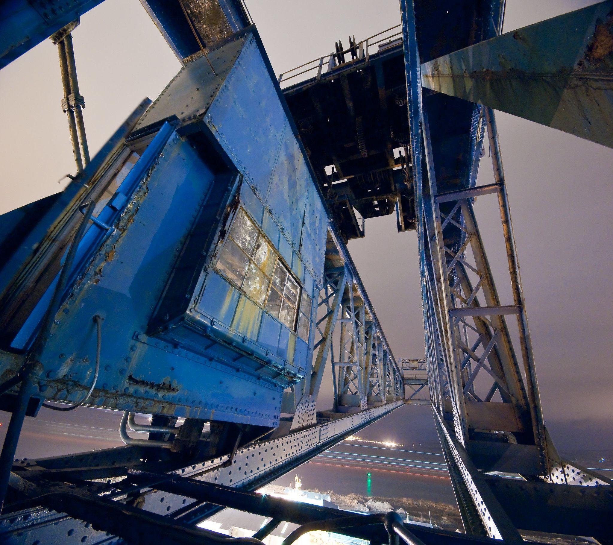 A blue painted crane photographed at night. The crane is constructed of giant latticed girders.