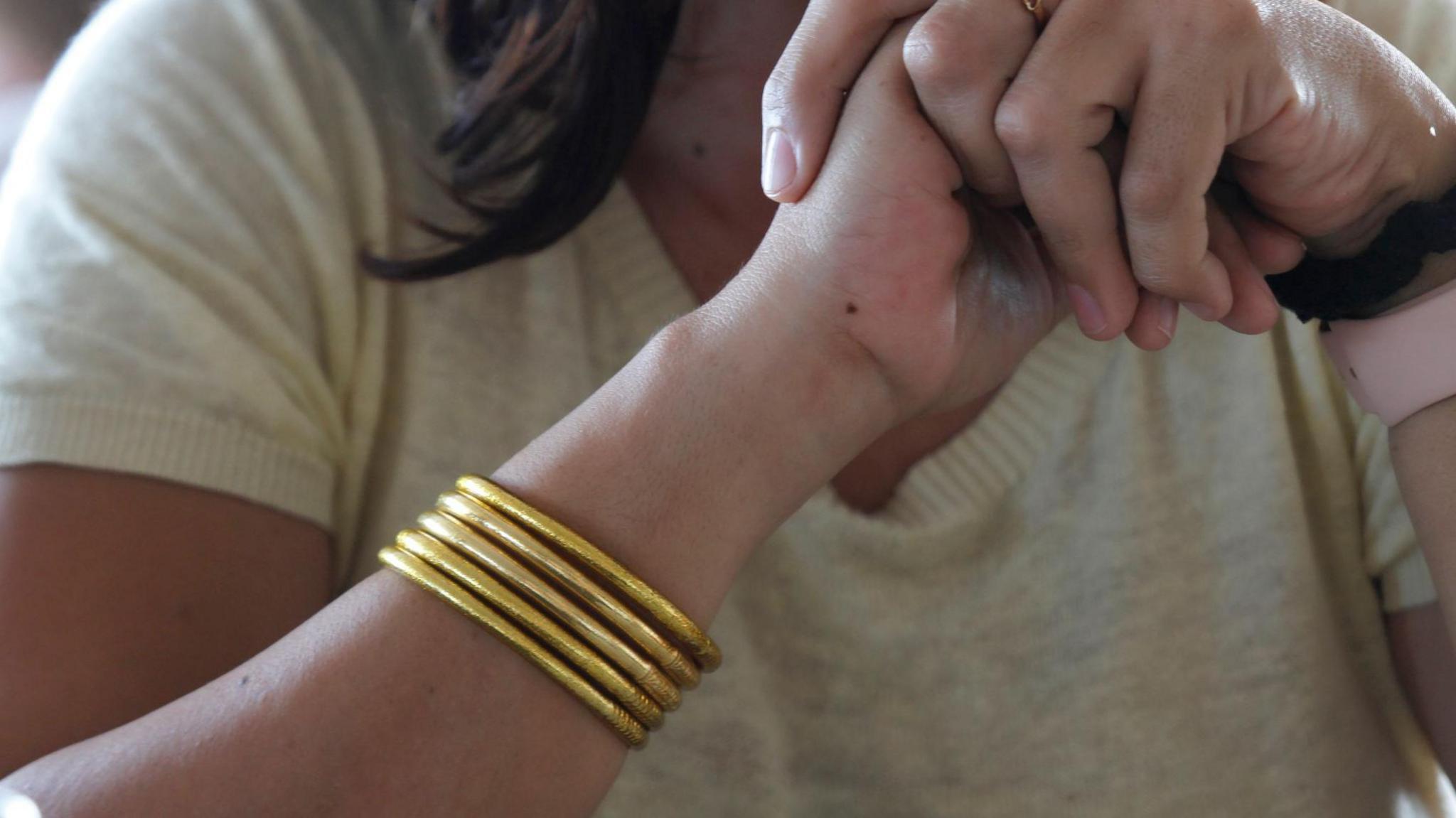 Gold bracelets on a person's arm