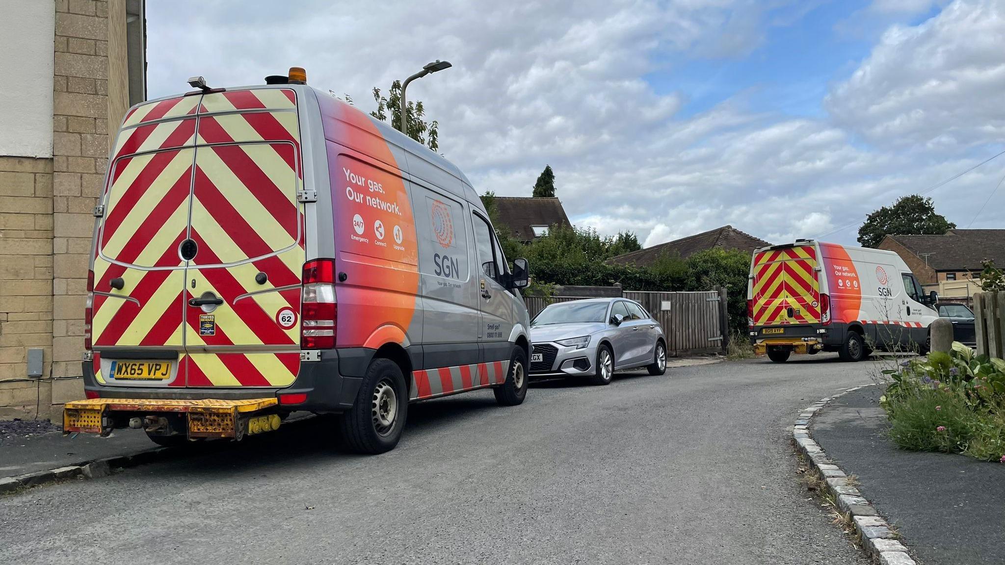 Two SGN vans parked on a bend with clouds behind them