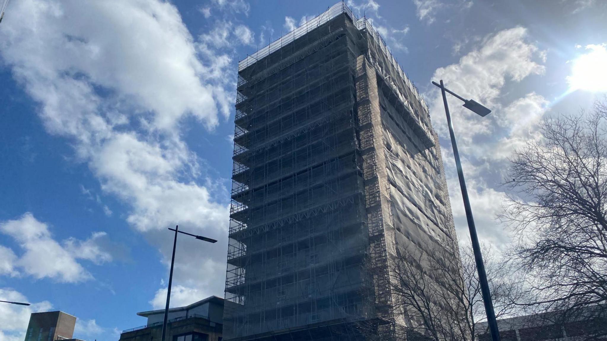 St Francis Tower with scaffolding around it. The photo is taken looking up at the building with a blue sky behind.