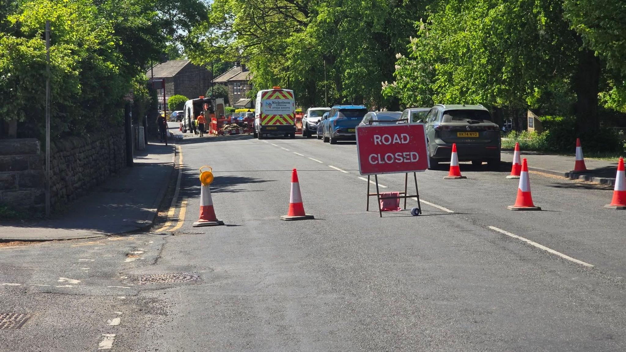A red 'road closed' sign with cones blocking the road.