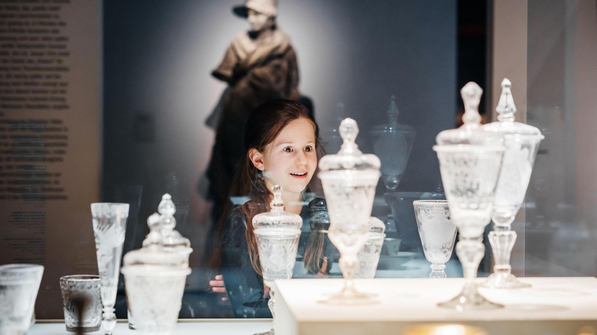 girl looking amazed at glass vases in a museum.