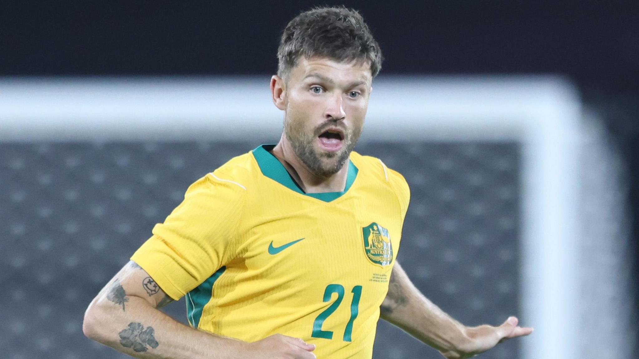 Cameron Burgess wearing a yellow Australia shirt with green trim on the neck.