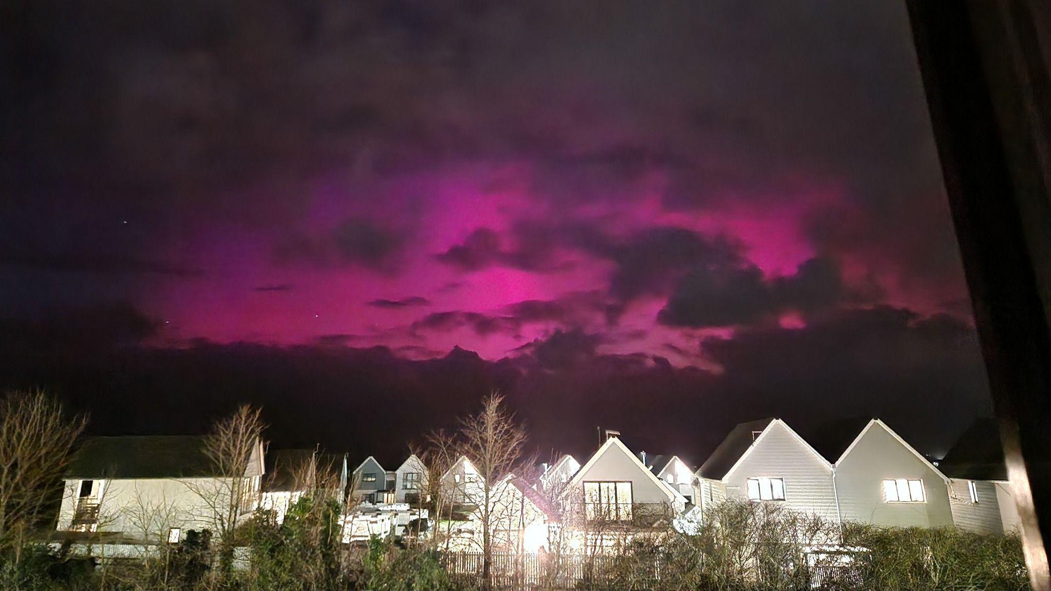 Pink skies lit up the dark sky over Westward Ho!. The northern lights are above residential houses.