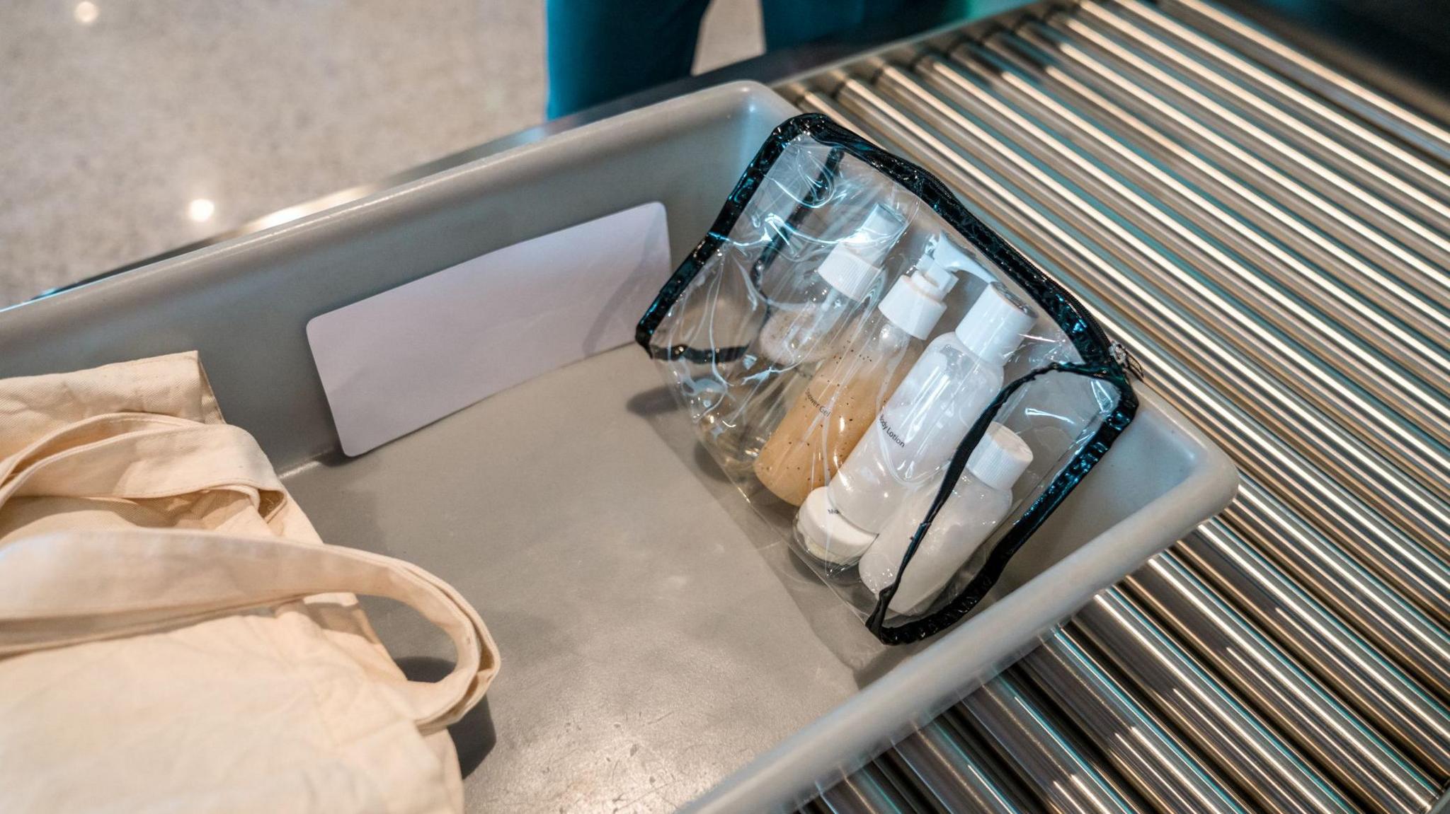 Small bottles of liquid in a see-through plastic bag traveling through an airport security scanner