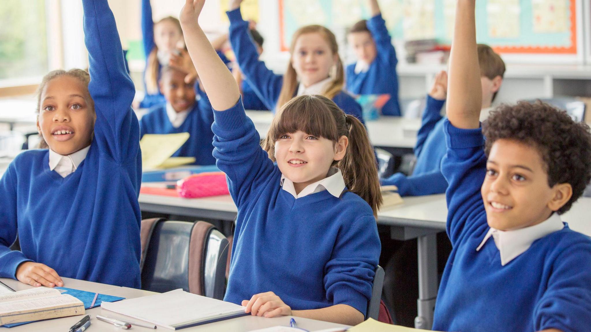 children at primary school with their hands up