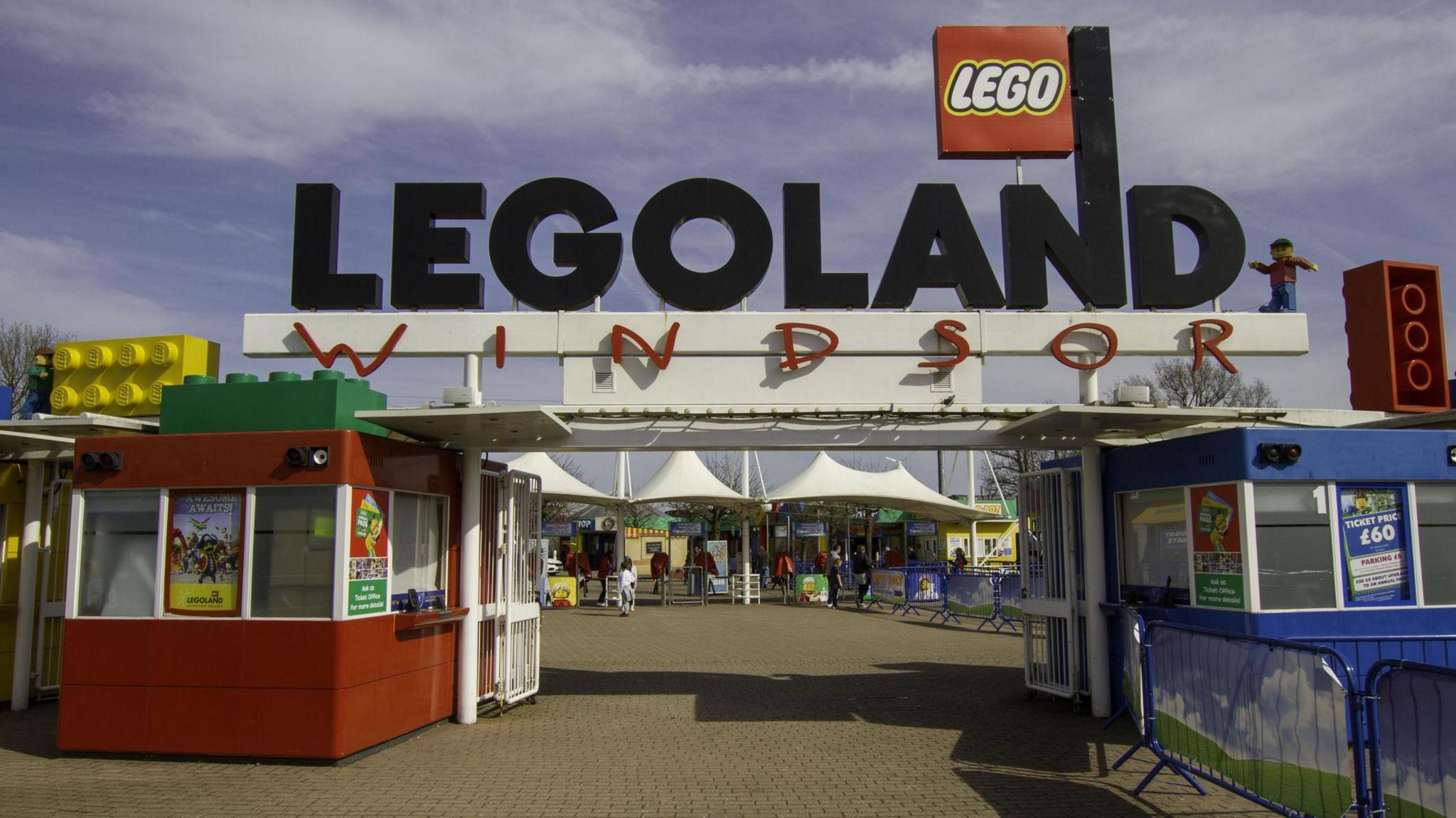 A general view picture of the entrance to Legoland Windsor, with two entrance kiosk on the left and right below a sign that says Legoland Windsor.