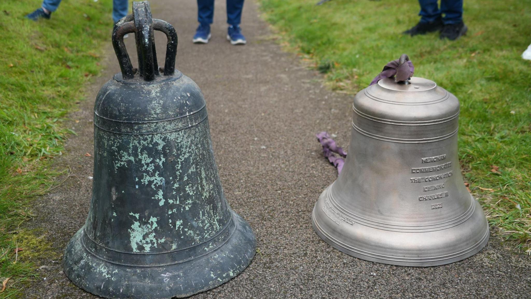 Two church bells side by side, one is a blueish bronze colour and the other is silvery looking