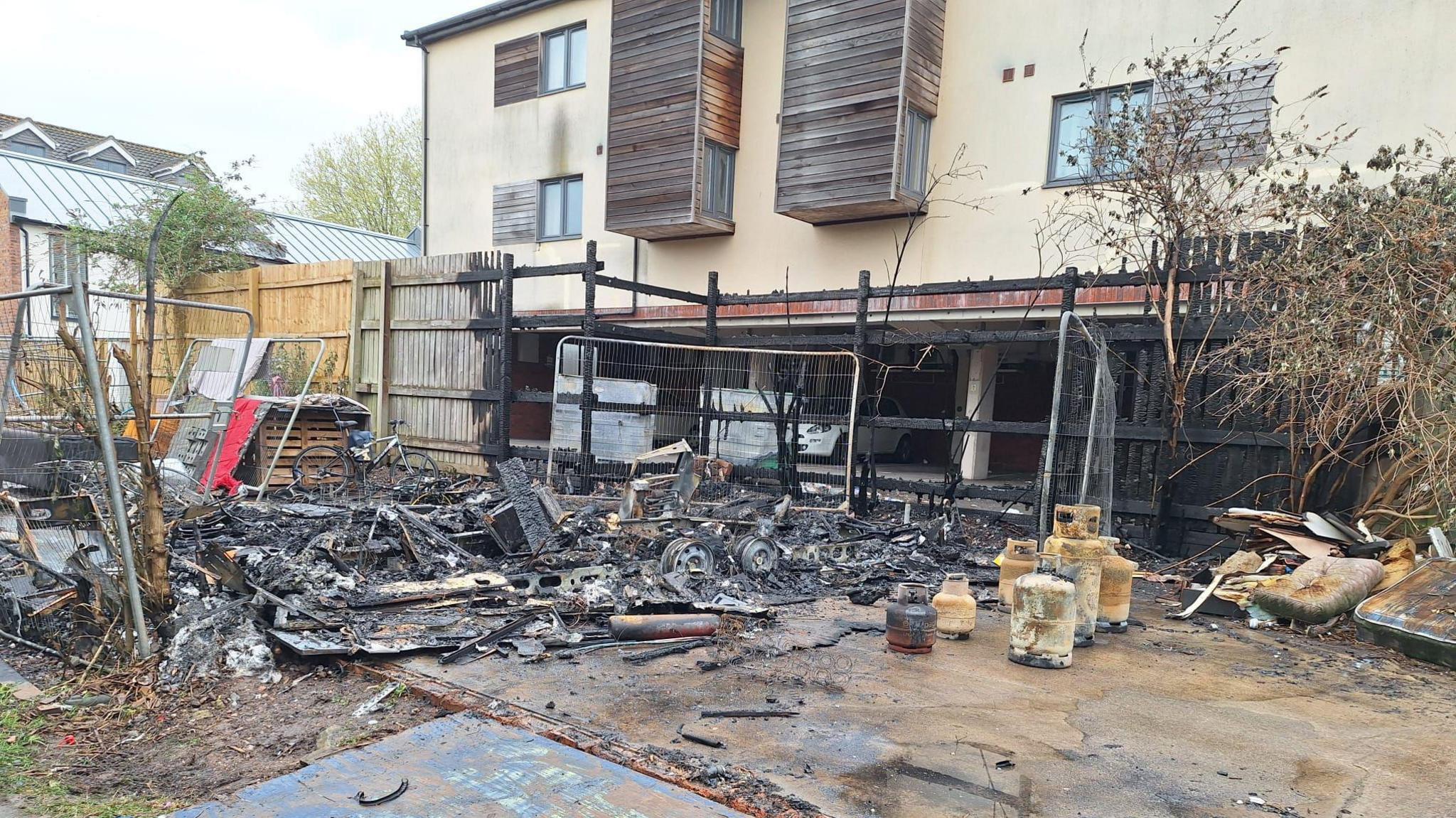 Charred remains of the caravan close to new block of flats in Bristol