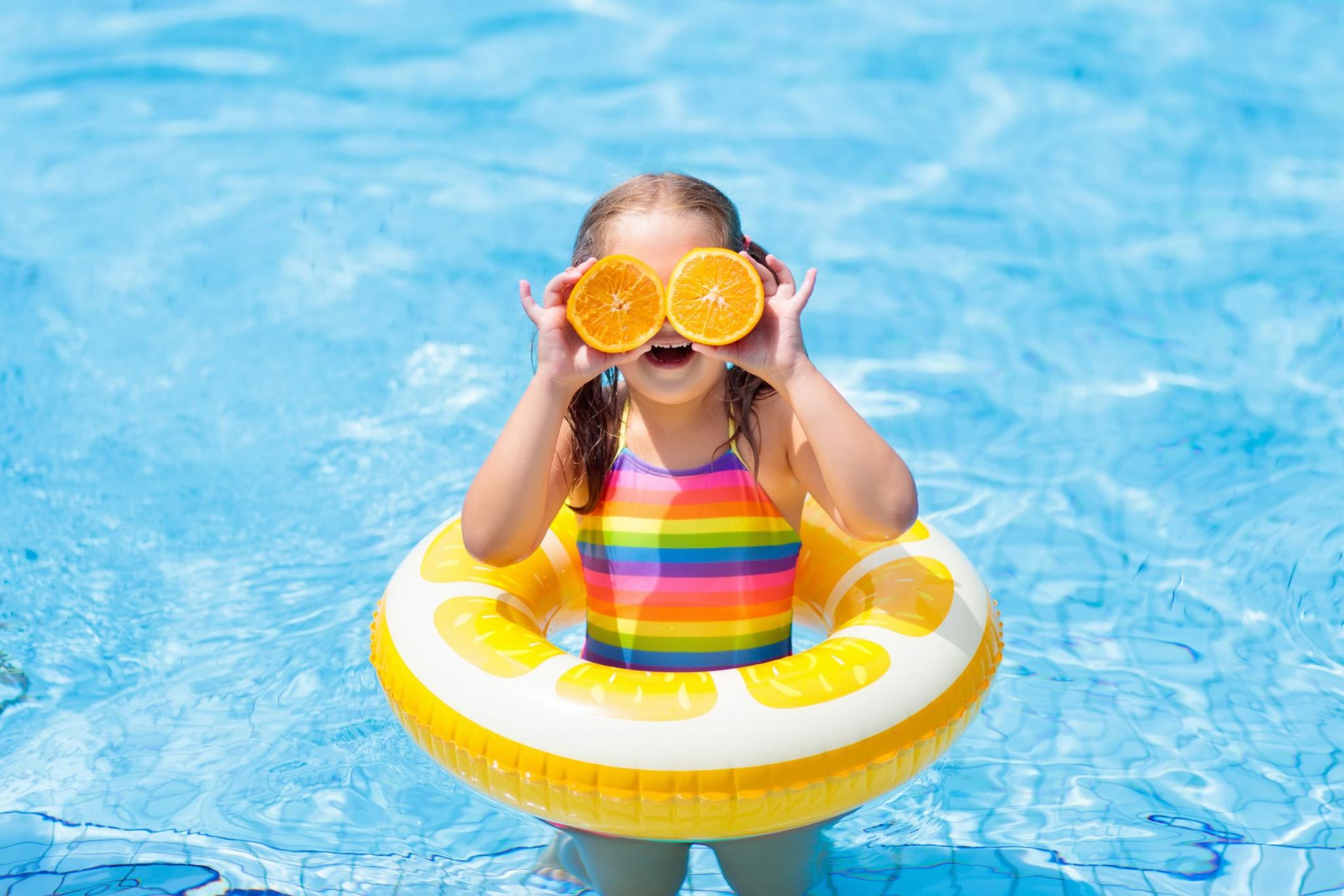 A girl in a swimming pool with oranges for eyes.