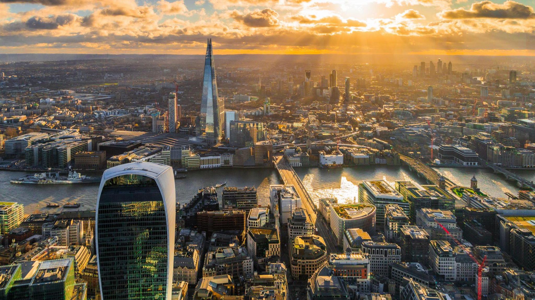 An aerial view of London, showing part of the City of London and the Shard on the south side of the river.