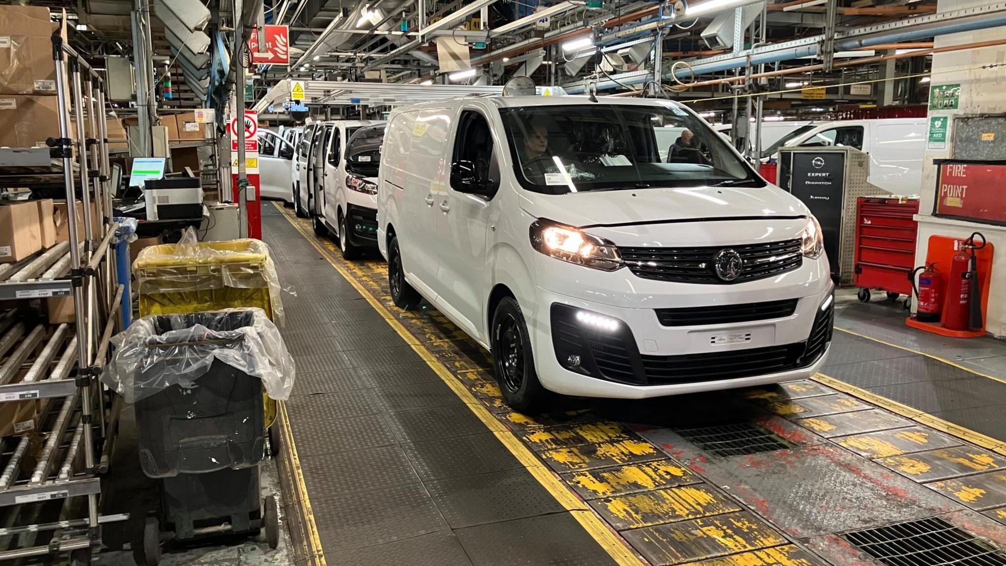 A white van on the production line at the Vauxhall plant in Luton, with several other vans behind and shelving alongside