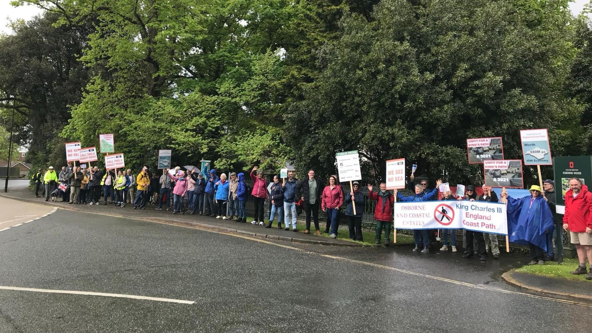 A crowd of protesters with banners next to a road