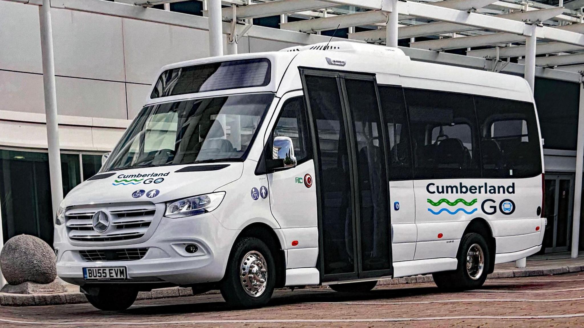 A small white bus has green and blue branding on it that reads: "Cumberland Go"