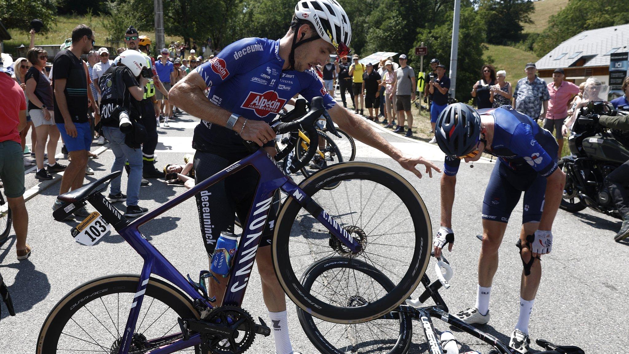 Riders check their bikes after a crash on stage 15