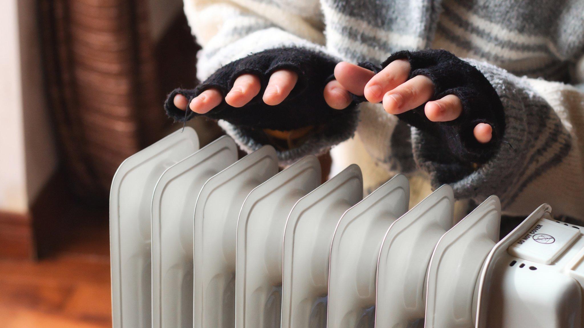 Person's hands warming above a radiator