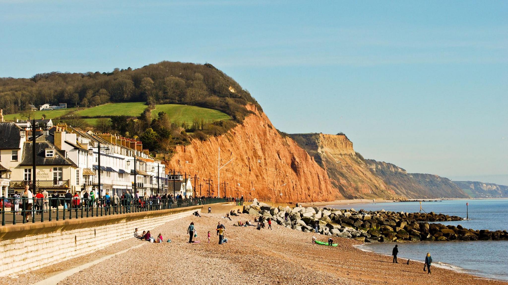 Sidmouth seafront with red cliffs of Jurassic Coast in Devon on a clear day.