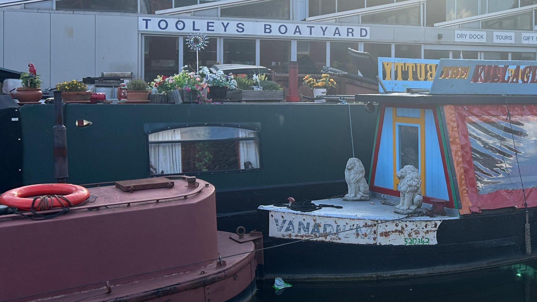 Three colourful canal boats in front of Tooley's Boatyard.