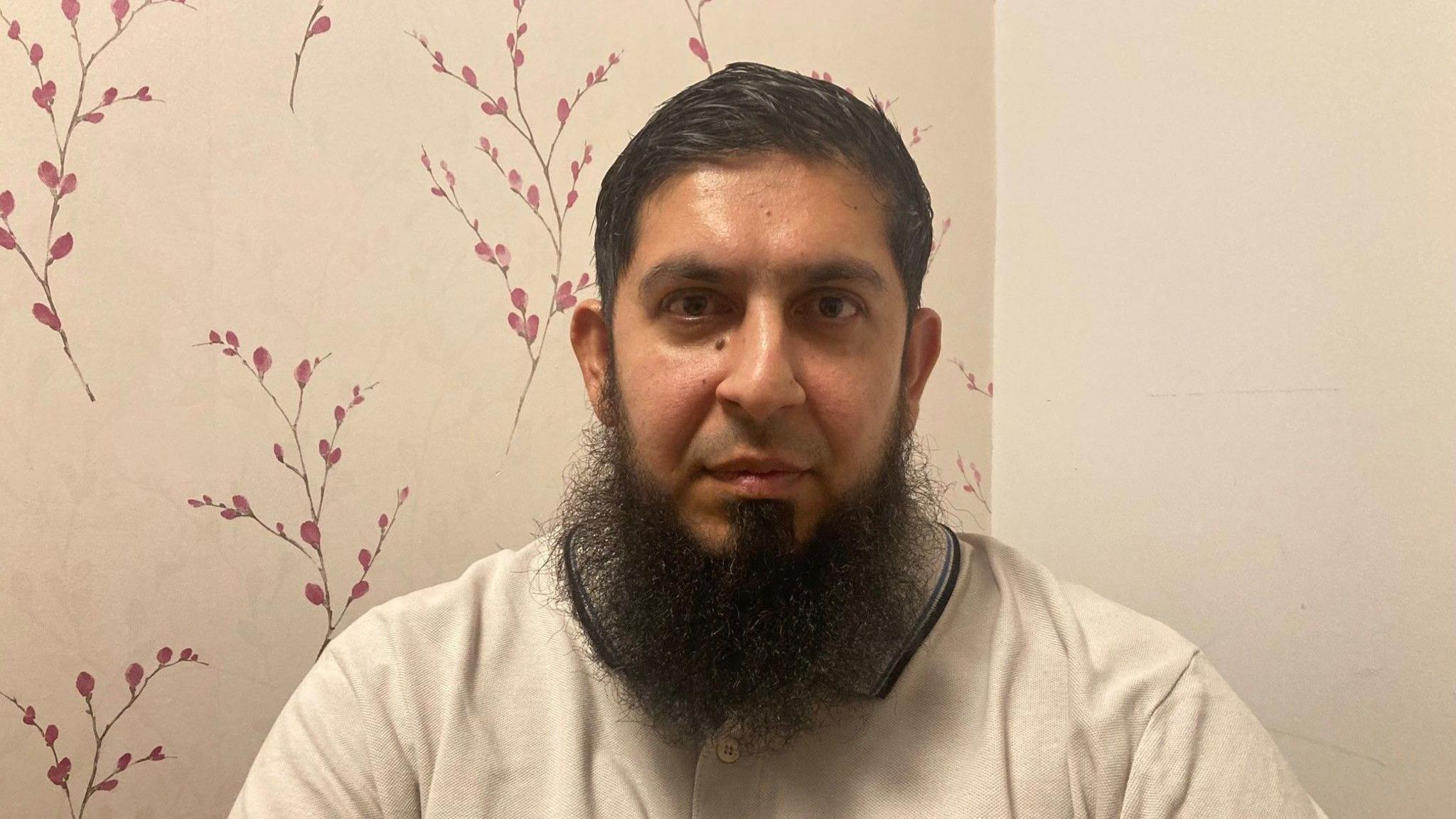 A man with a long beard wearing a cream 