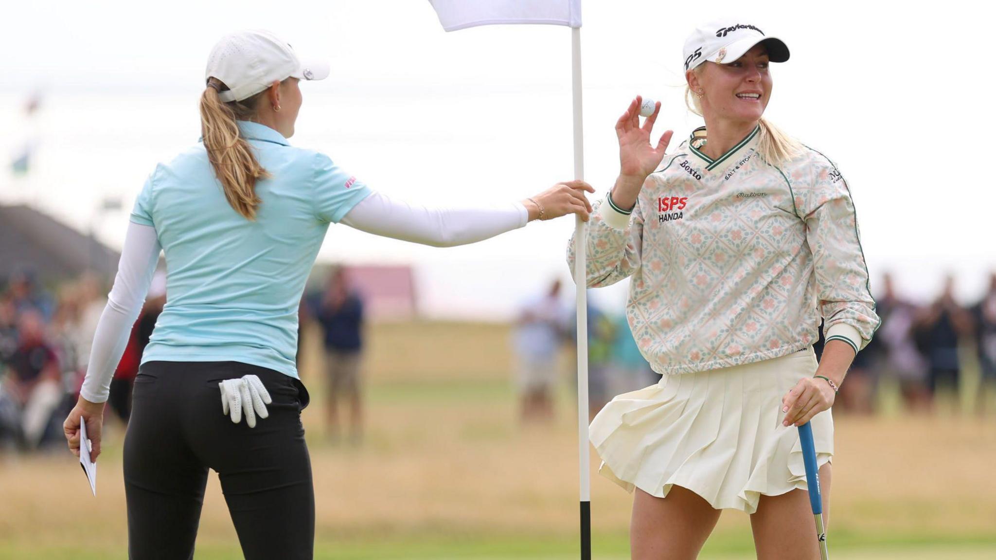 Charley Hull raises her ball in celebration after finishing her round at the Women's Open