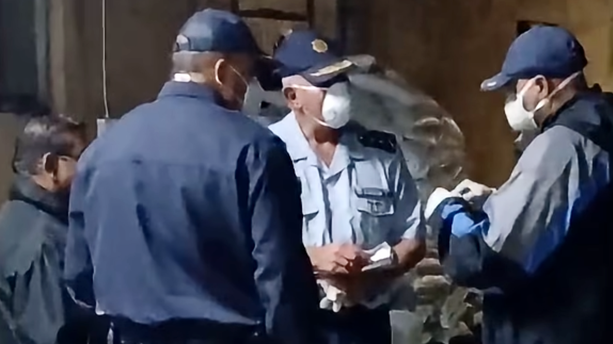Three officers in face masks and uniform in discussion during a raid on a meth lab found at a farm in Limpopo province
