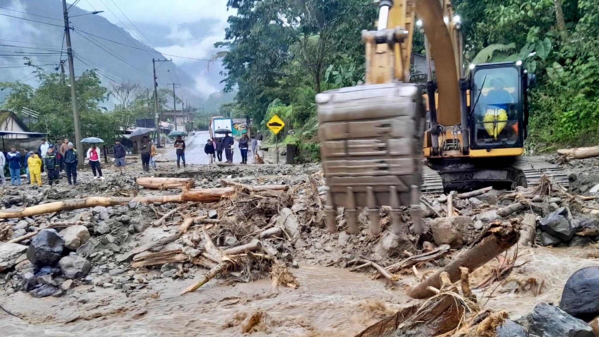 A digger removes debris from a road near Baños