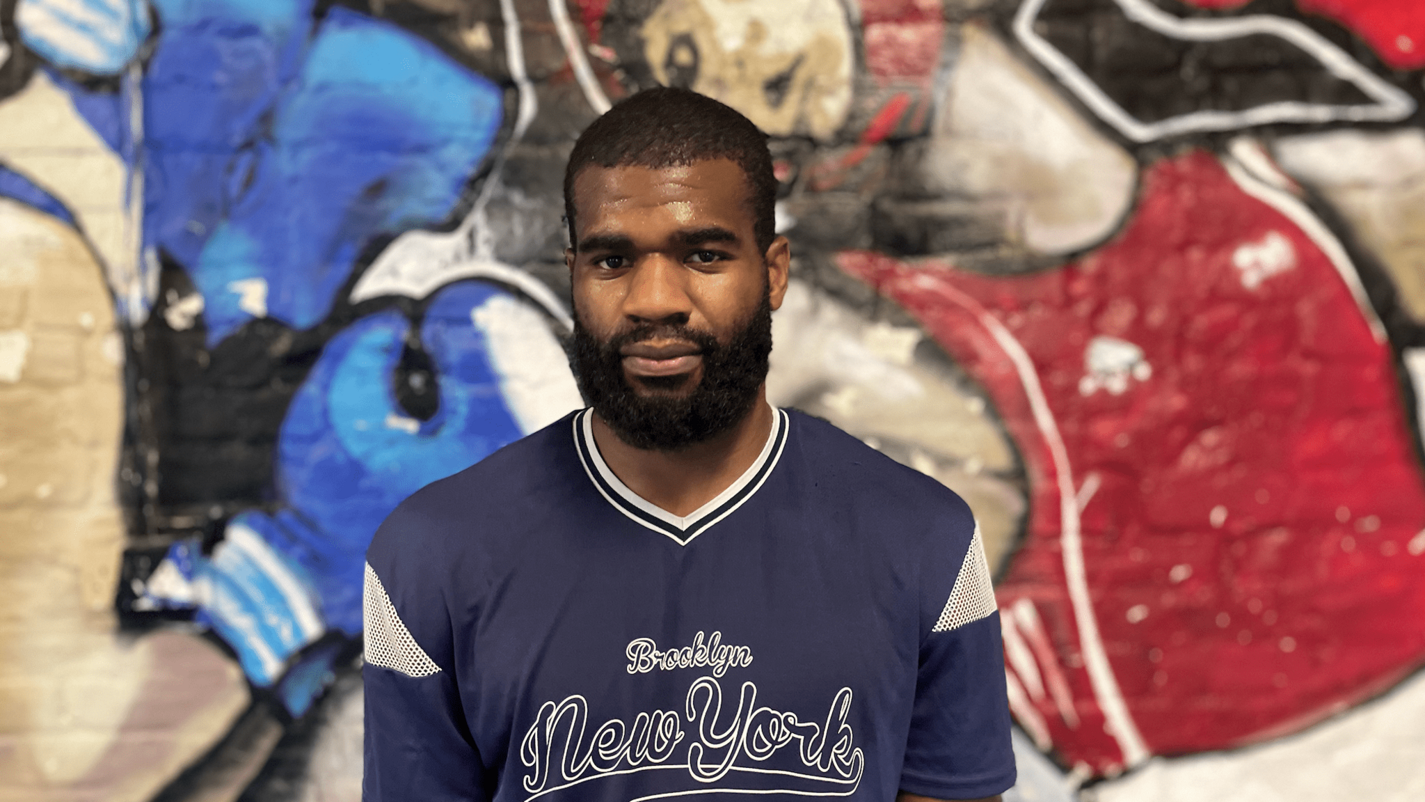 Babatunde Duyile standing by a graffiti wall at White Cliffs Boxing Gym