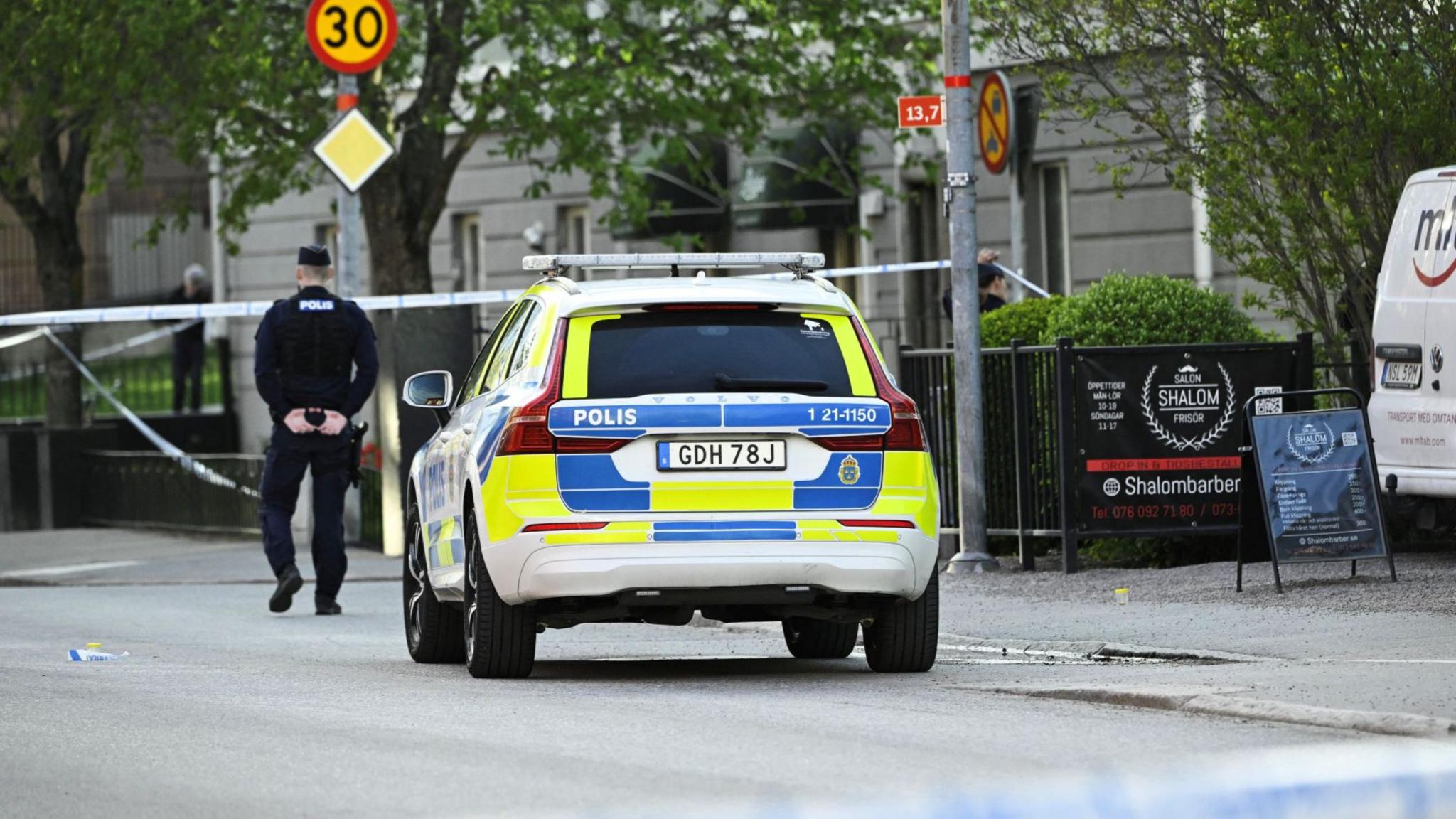 A police officer and police car next to a cordon at the scene of the shooting