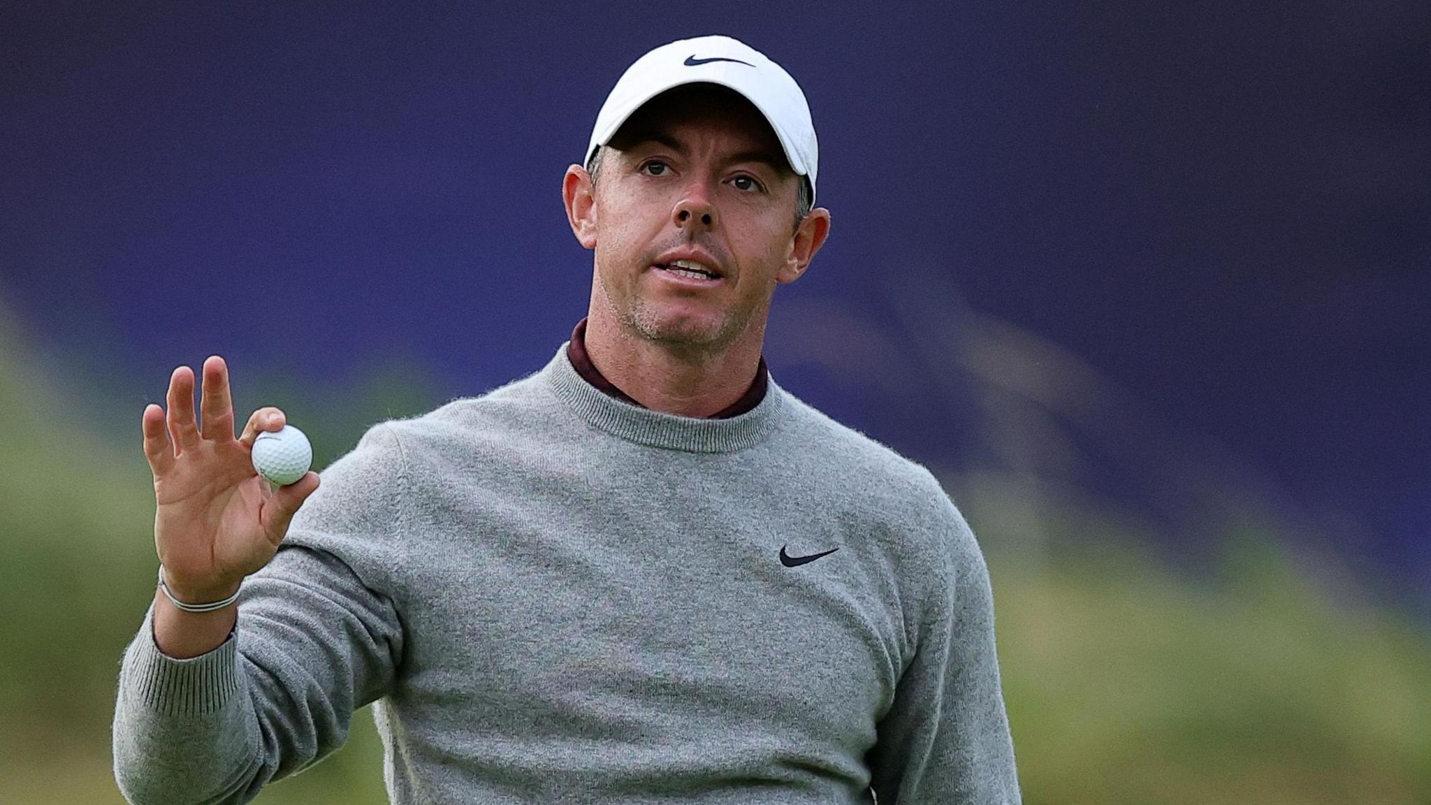 Rory McIlroy holds his golf ball up as he receives applause from the crowd