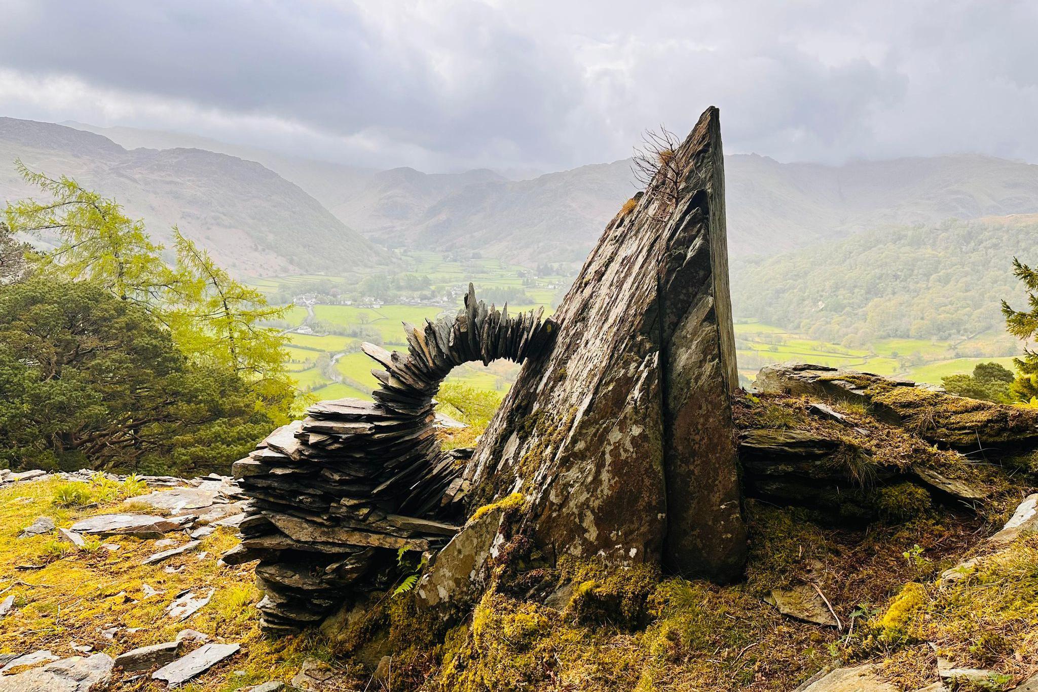 Flat slate and stones piled on top of each other in a curve against a rock face