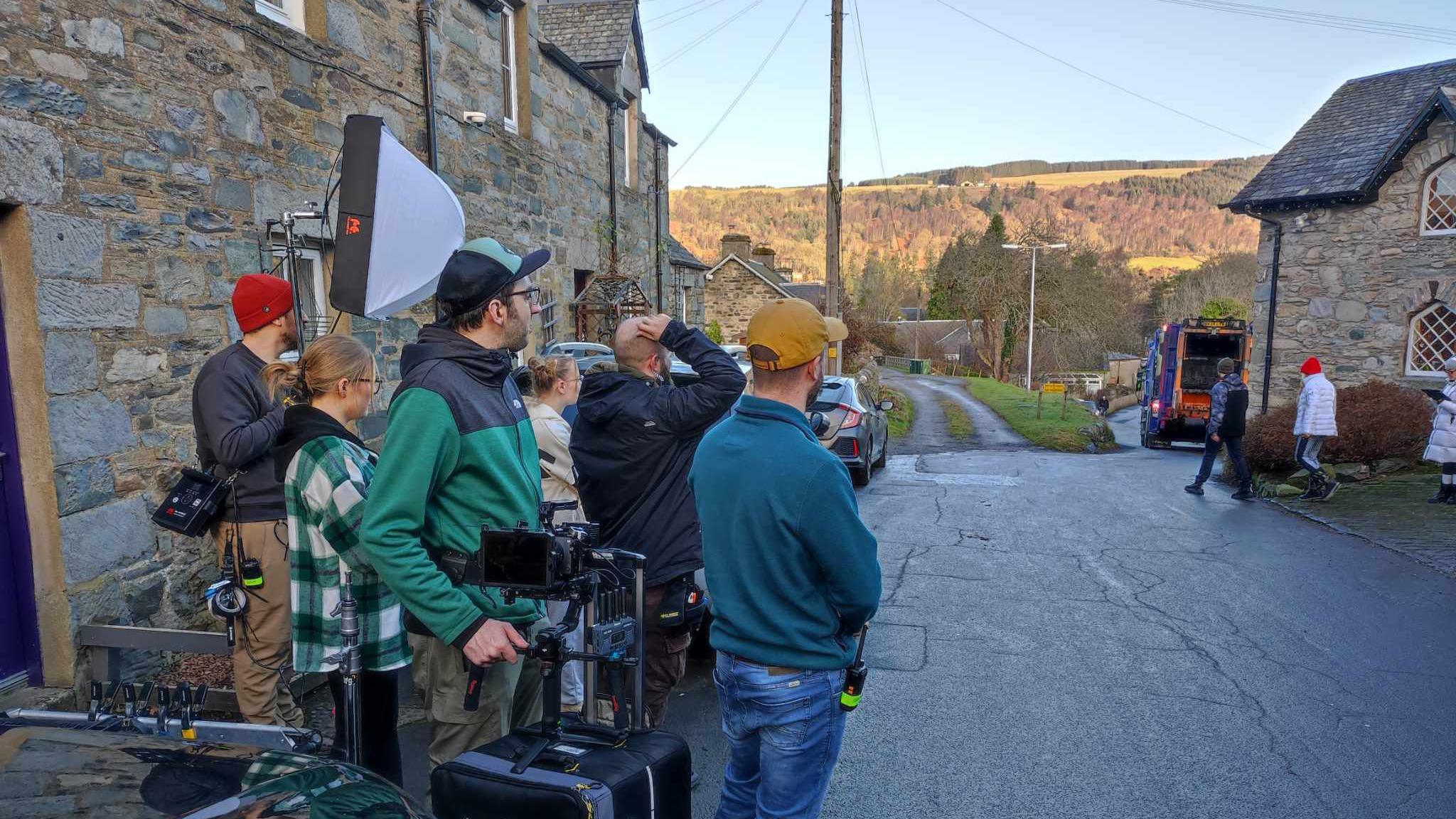 Crew members set up in the street outside the café while producer Caprice looks around.