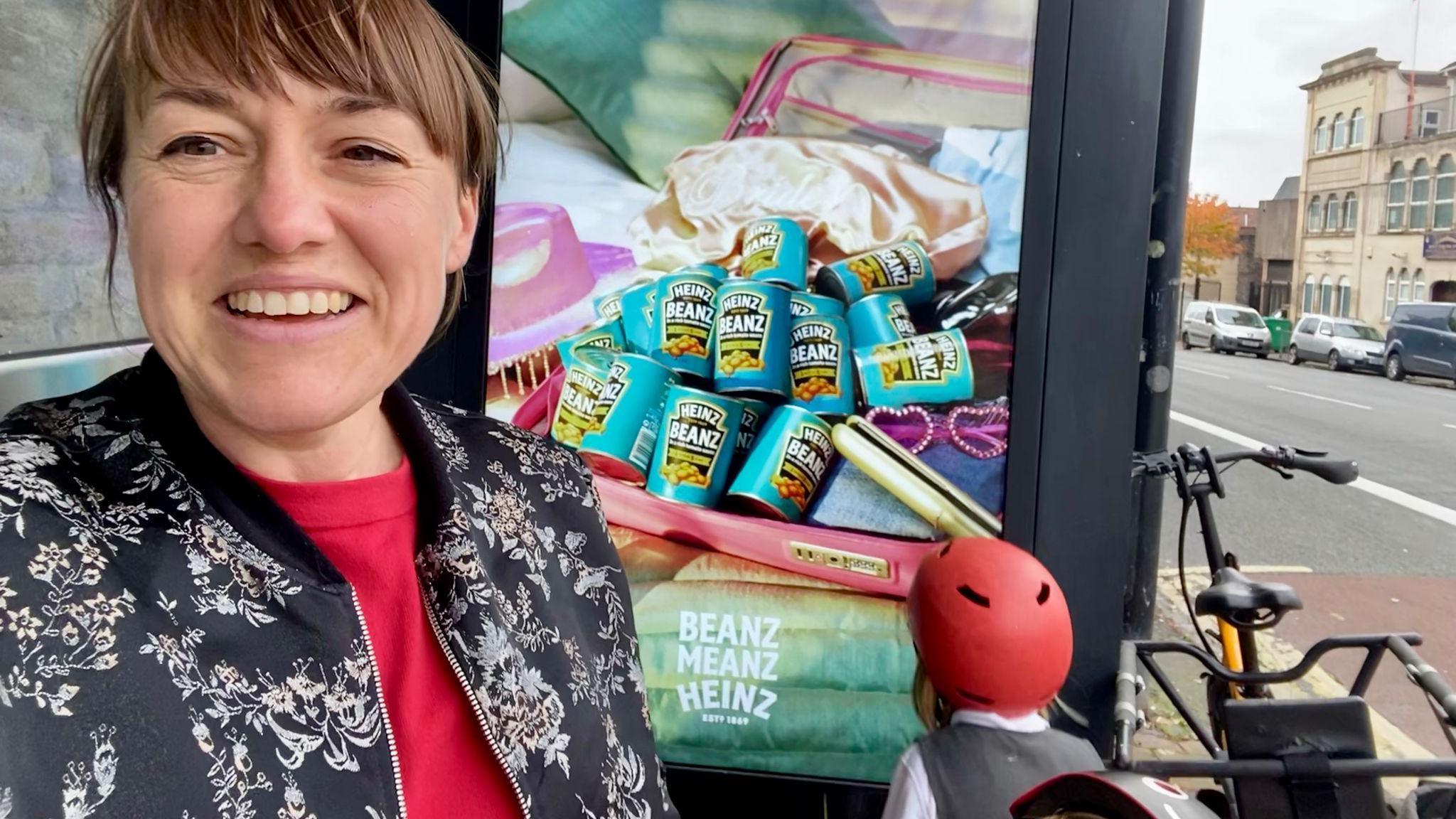 Anna with her children next to a bus stop advert for Heinz Beans