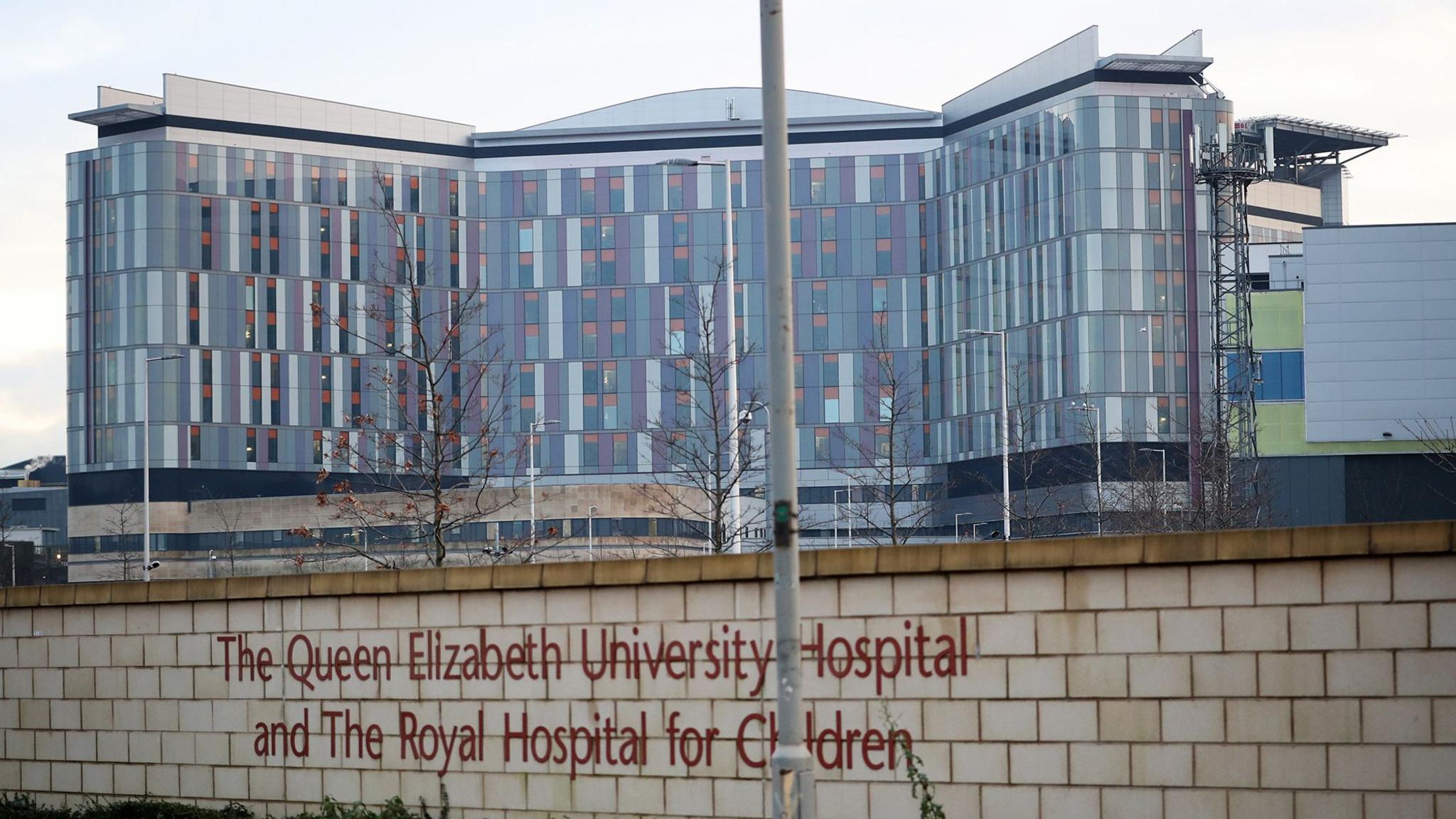 A large modern hospital building with the words Queen Elizabeth University Hospital and Royal Hospital for Children written on a wall in the foreground