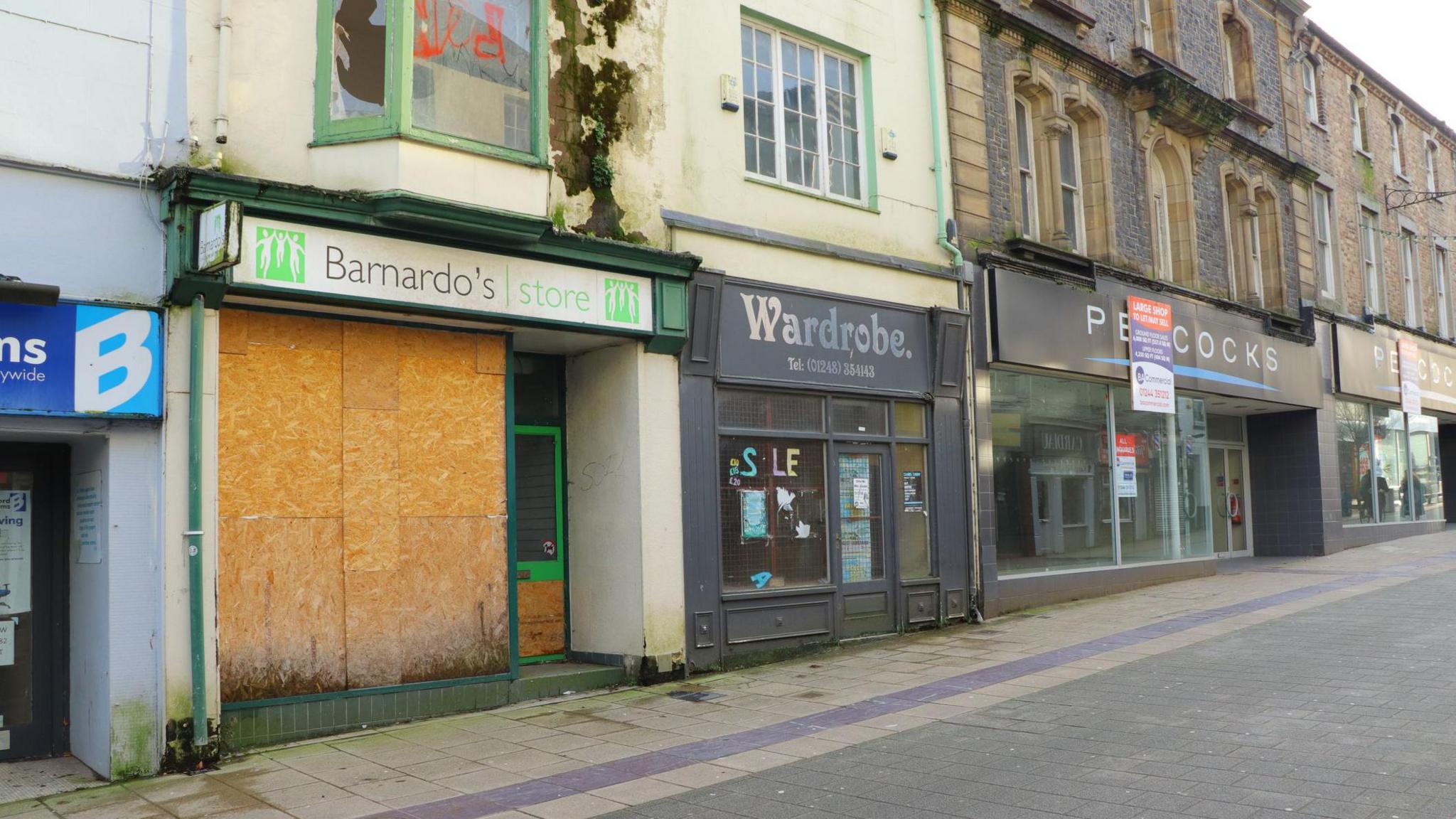 A row of shops, many looking run down or shut up.