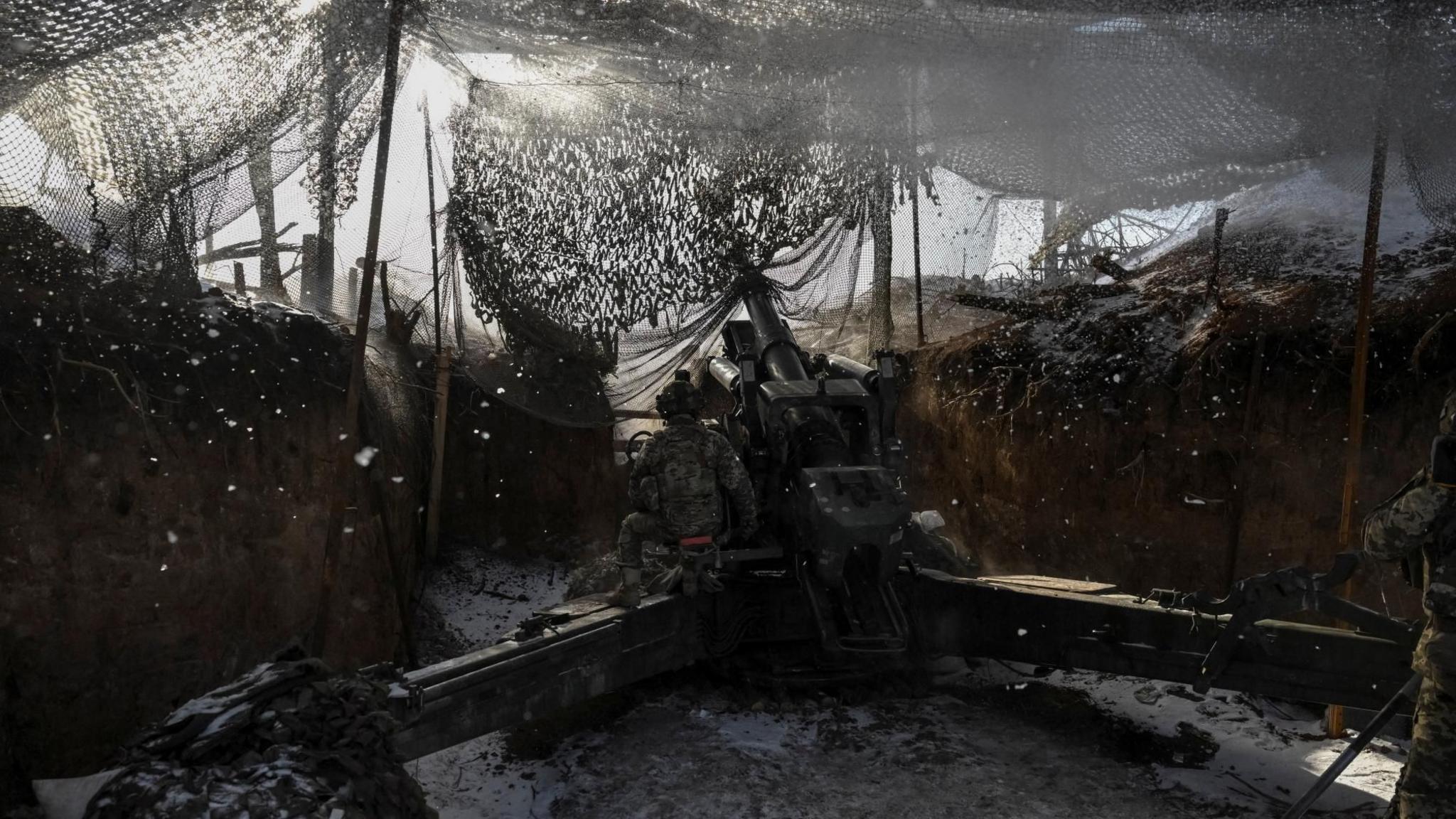 A Ukrainian soldier operating an artillery weapon from a trench in eastern Ukraine