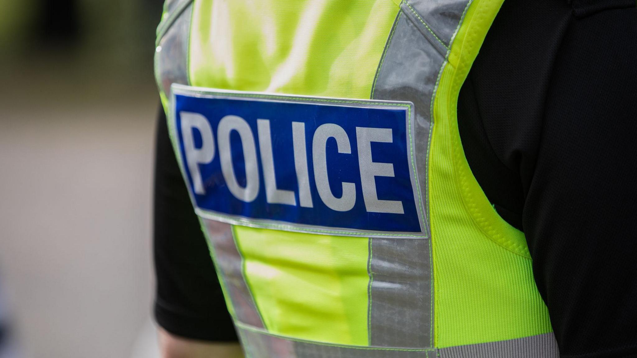 A police officer wearing a high vis jacket with the word police on the back