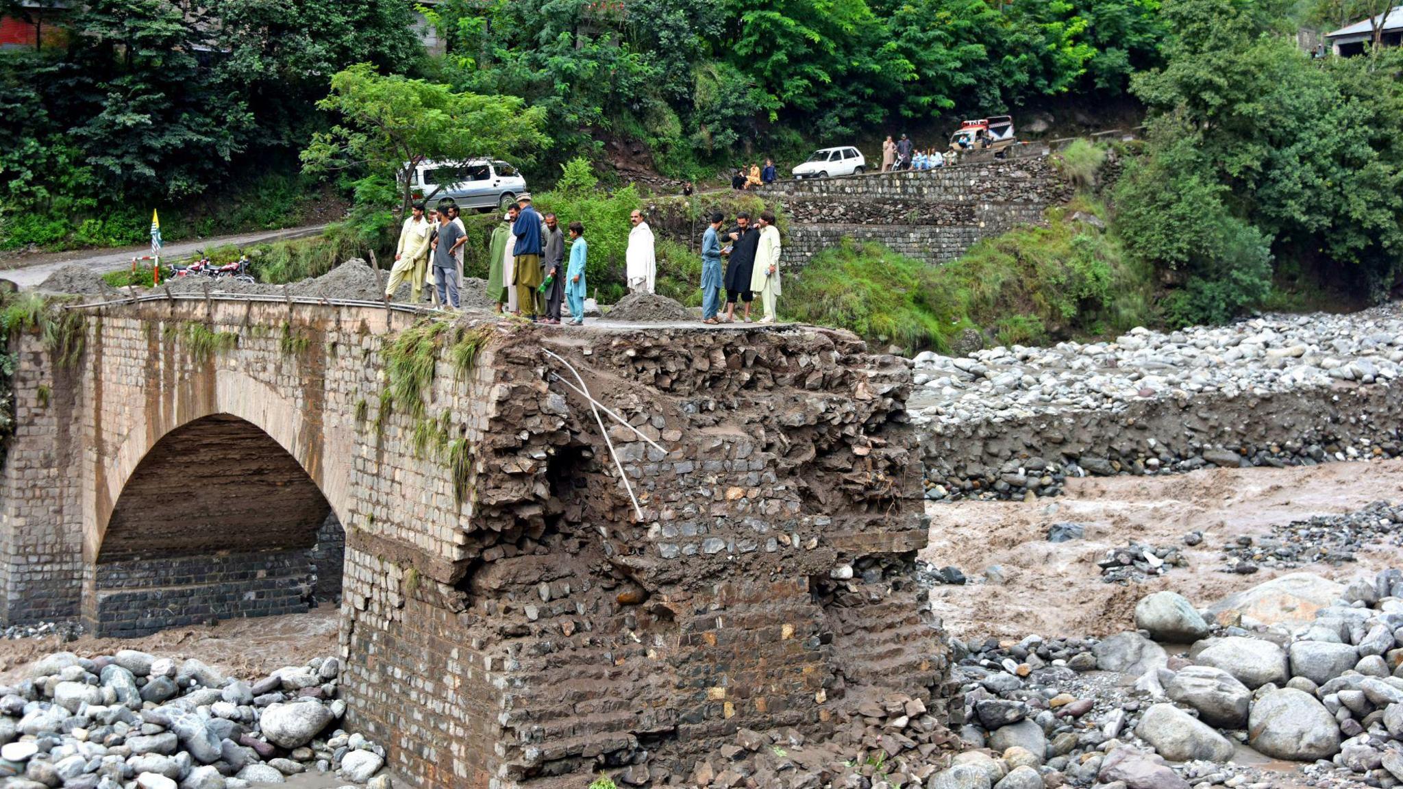 Onlookers gather near a destroyed bridge after flash floods on the outskirts of Muzaffarabad, the capital of Pakistan-administered Kashmir, on August 15, 2025