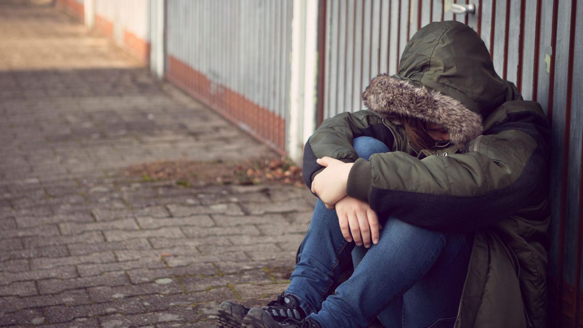 Anonymous teenage boy sitting outside