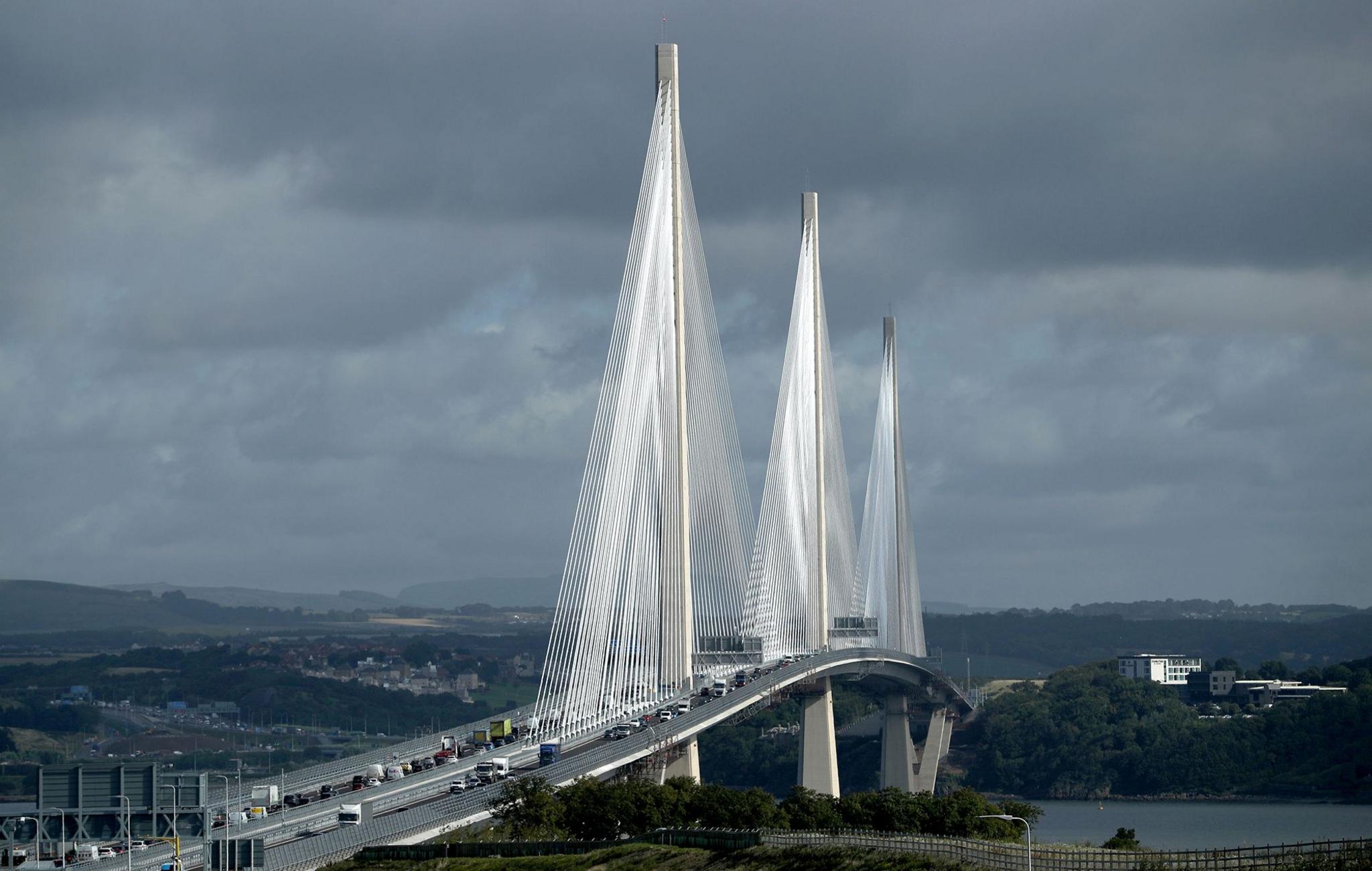 The three towers of the Queensferry Crossing with cables supported the arched rise of the motorway which is busy with traffic