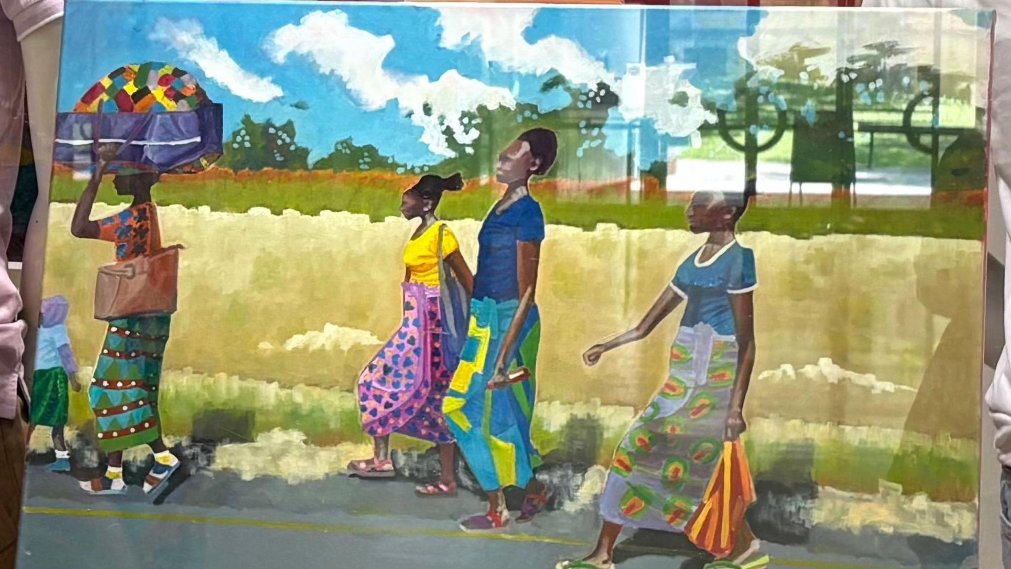 A painting of women in African traditional dress walking down a road. One is carrying a parcel on her head. 