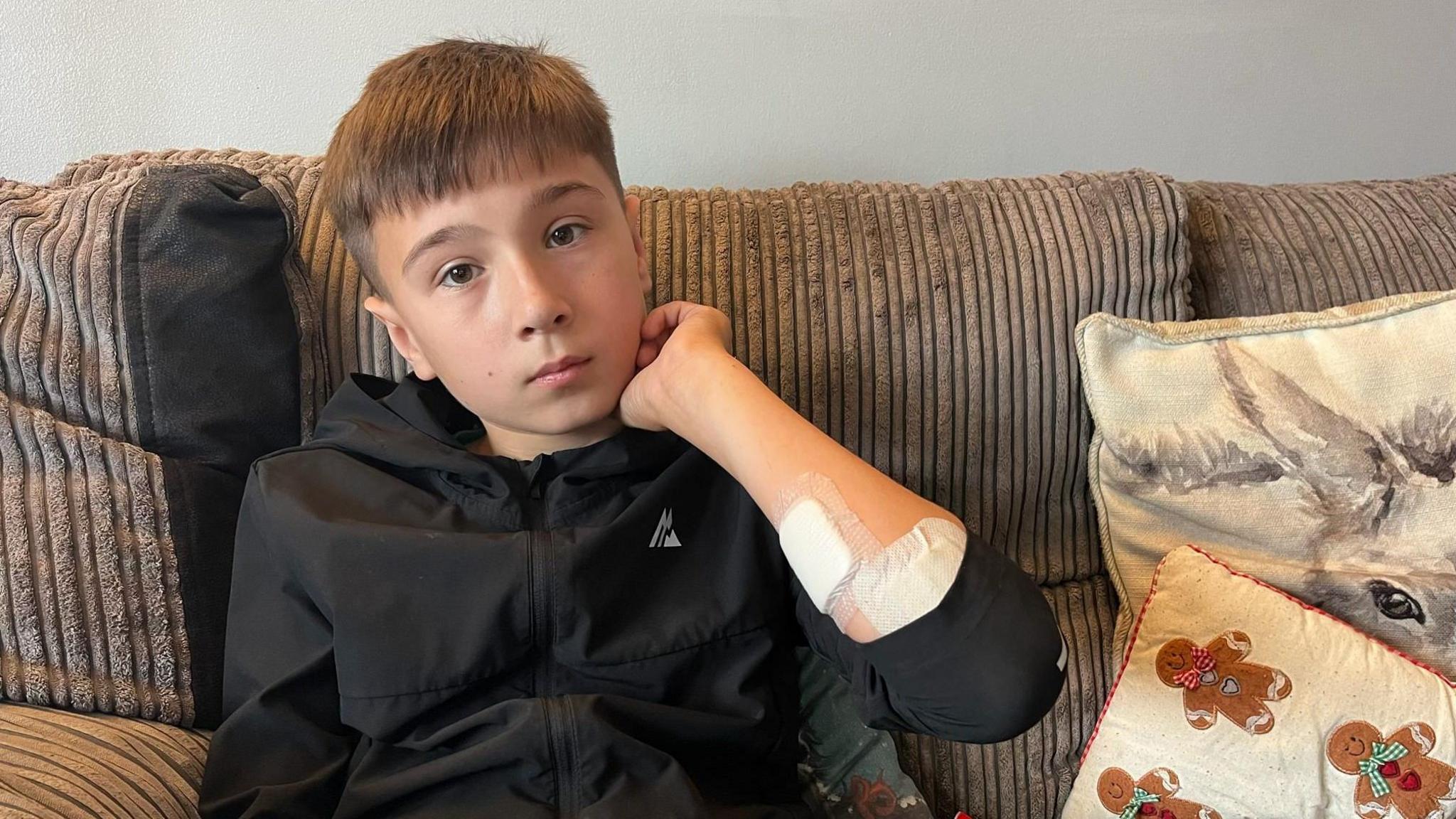 A boy on a sofa with bandages on his arms