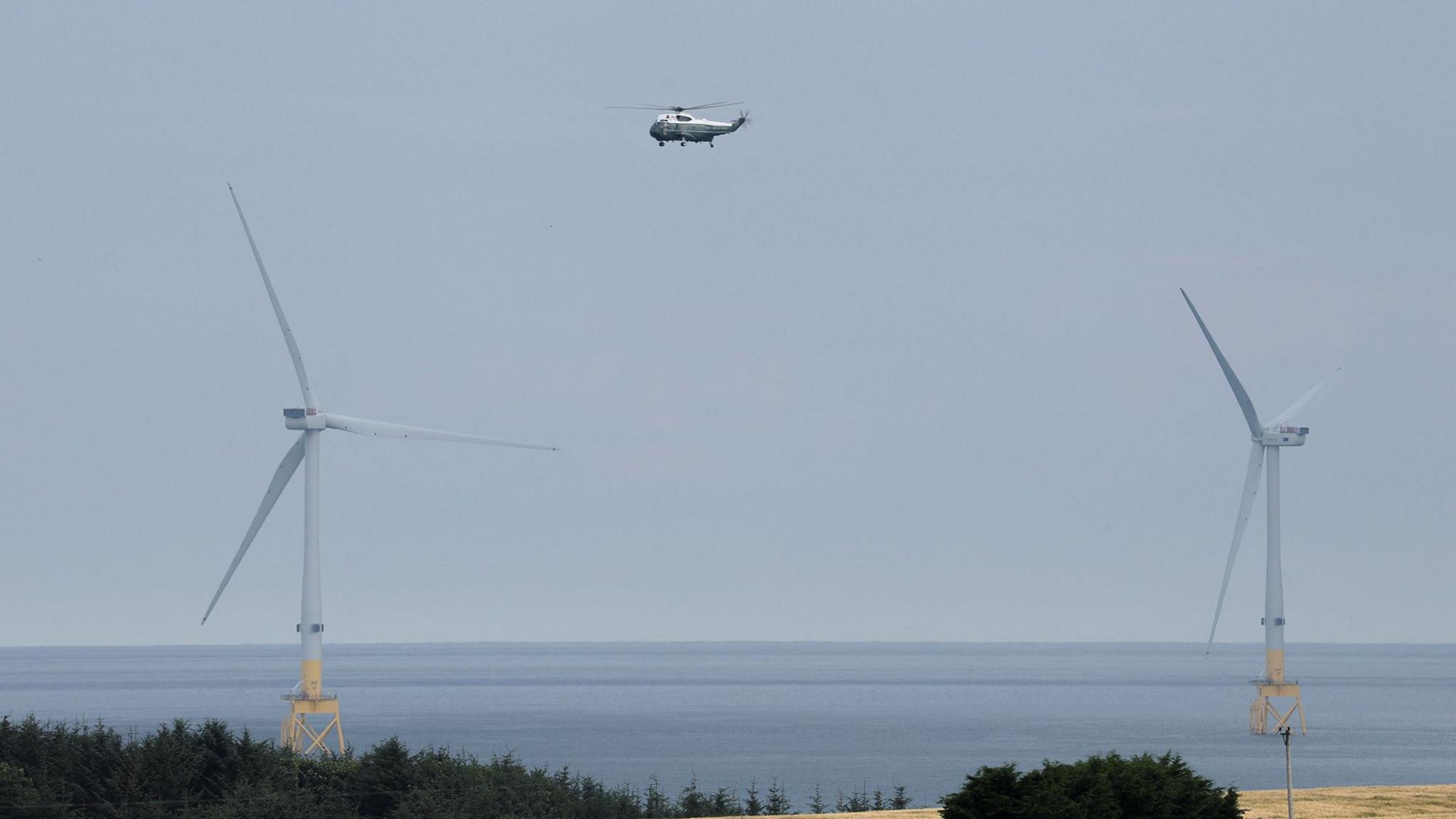 A helicopter in between two offshore wind turbines